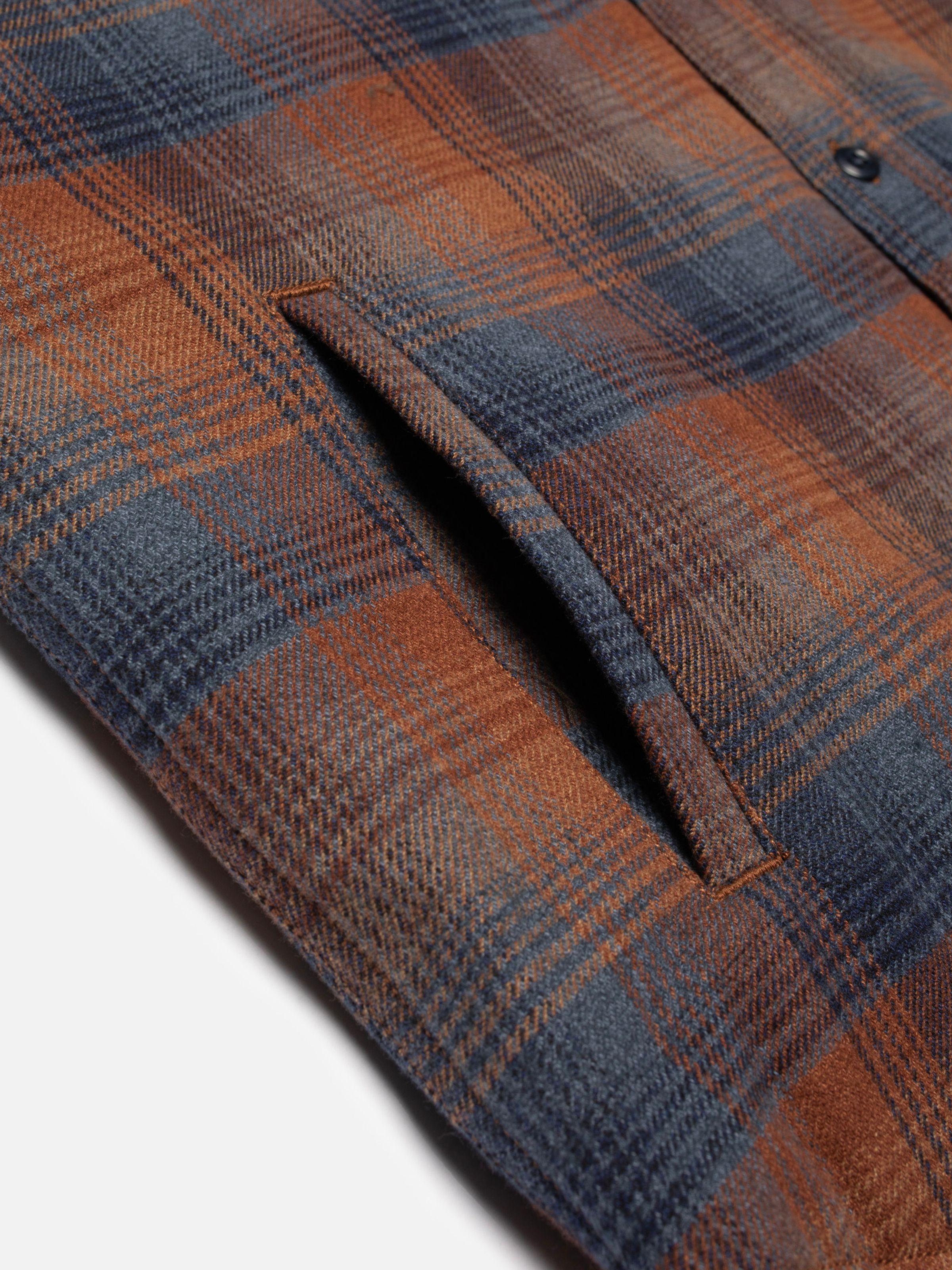 Nudie Jeans Glenn Padded Shirt Check Multi, a close-up of the side welt pocket and multi-colored check organic cotton fabric.