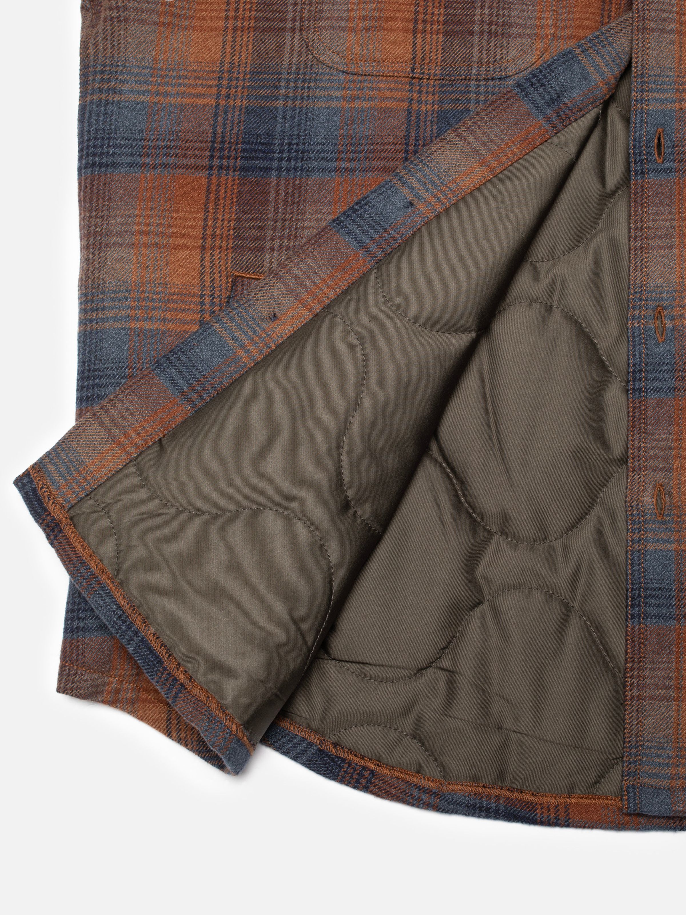 Nudie Jeans Glenn Padded Shirt Check Multi, close-up of the brown organic cotton plaid fabric and quilted lining.