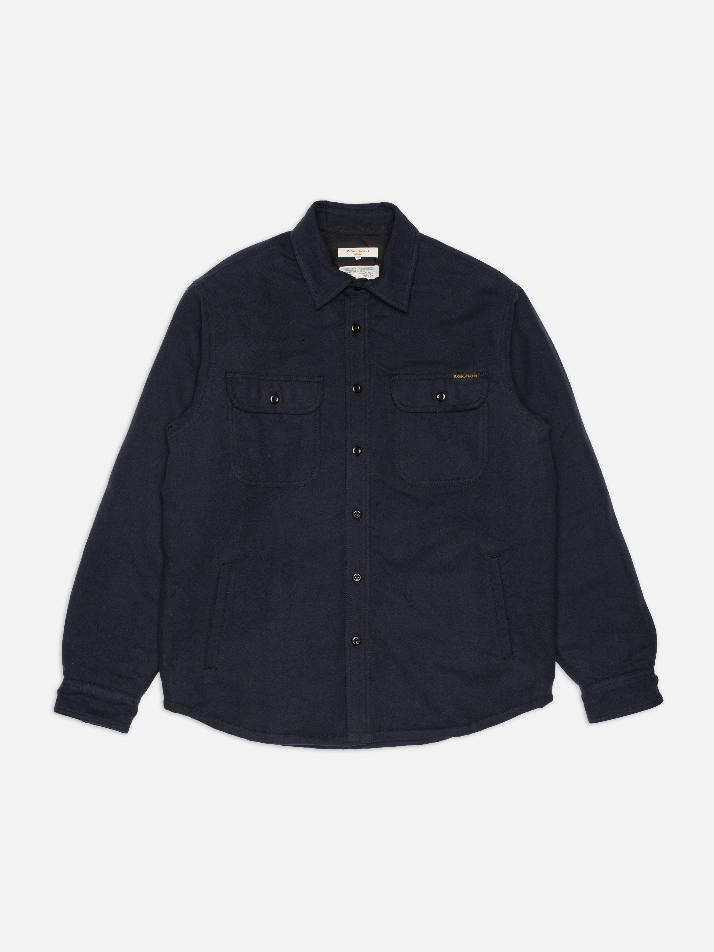 Nudie Jeans Glenn Padded Shirt Flannel Blueberry, ein dunkelblaues wattiertes Overshirt aus Bio-Baumwolle, flach liegend.