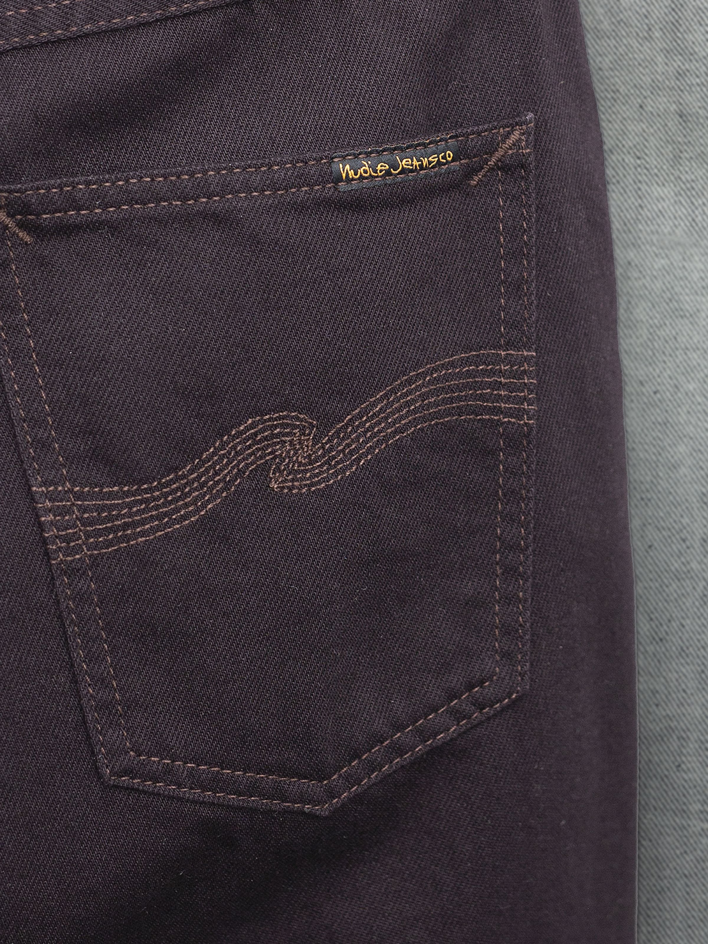 Nudie Jeans Rad Rufus Everbrown, Nahaufnahme des dunkelbraunen Rigid-Denim-Stoffs und der Gesäßtaschendetails.