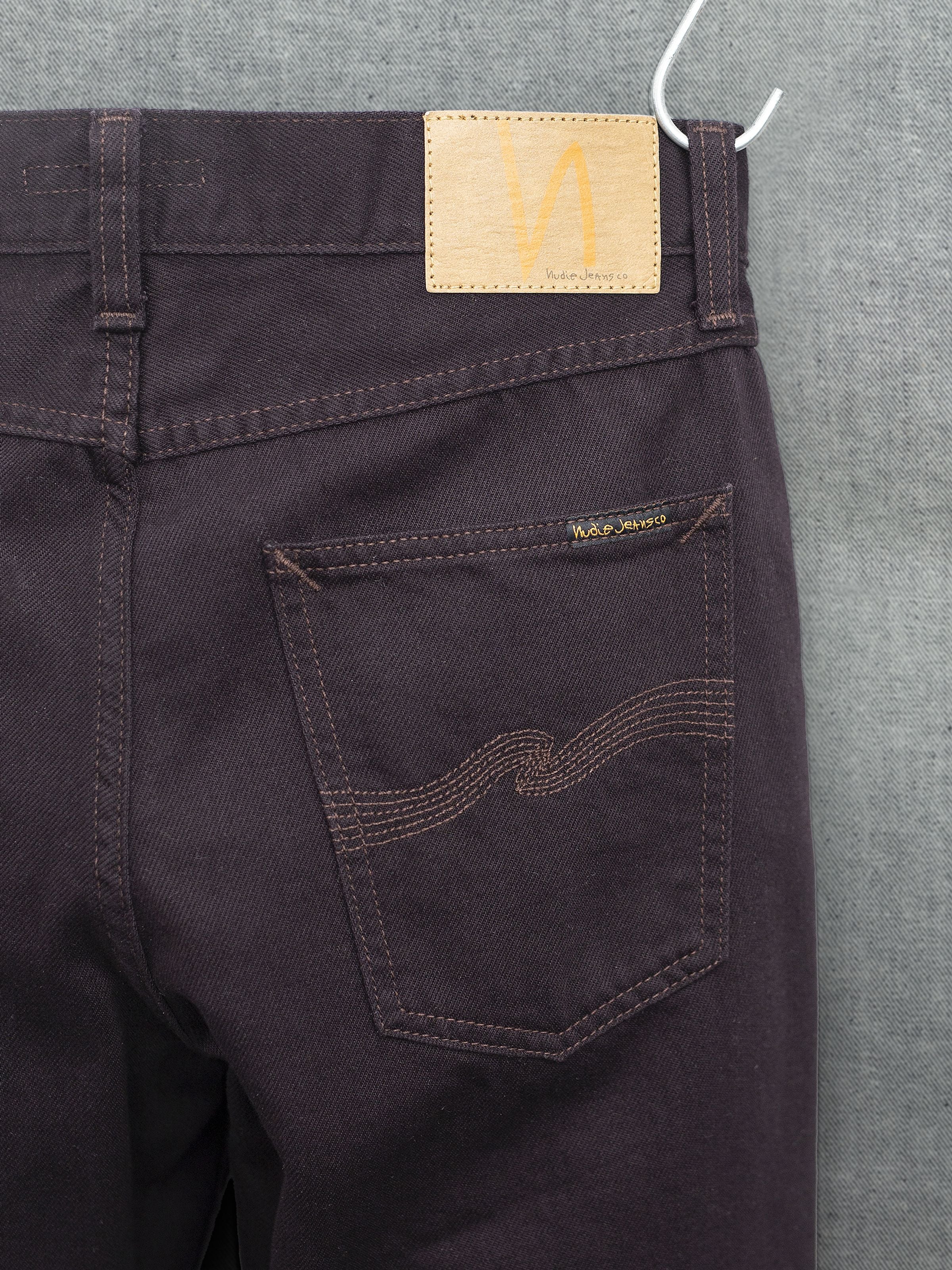 Nudie Jeans Gritty Jackson Everbrown, Gesäßtasche und Jacron-Patch auf tiefbraunem Rigid Denim aus Bio-Baumwolle.