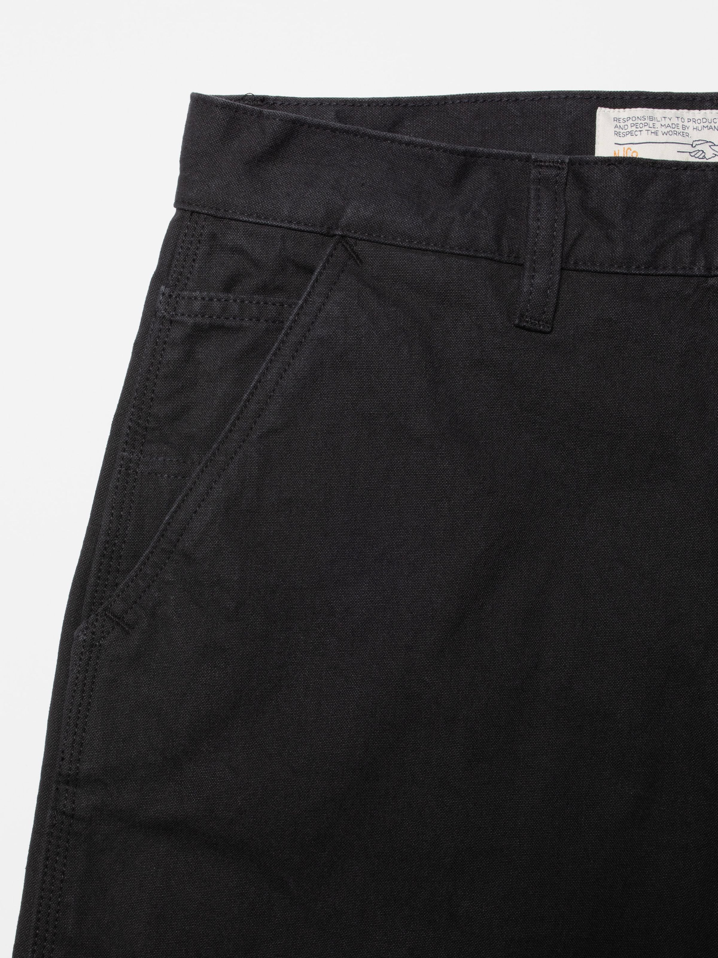 Nudie Jeans Tuff Tony Pants in black Duck Canvas, a close-up highlighting the front pocket and textured organic cotton.