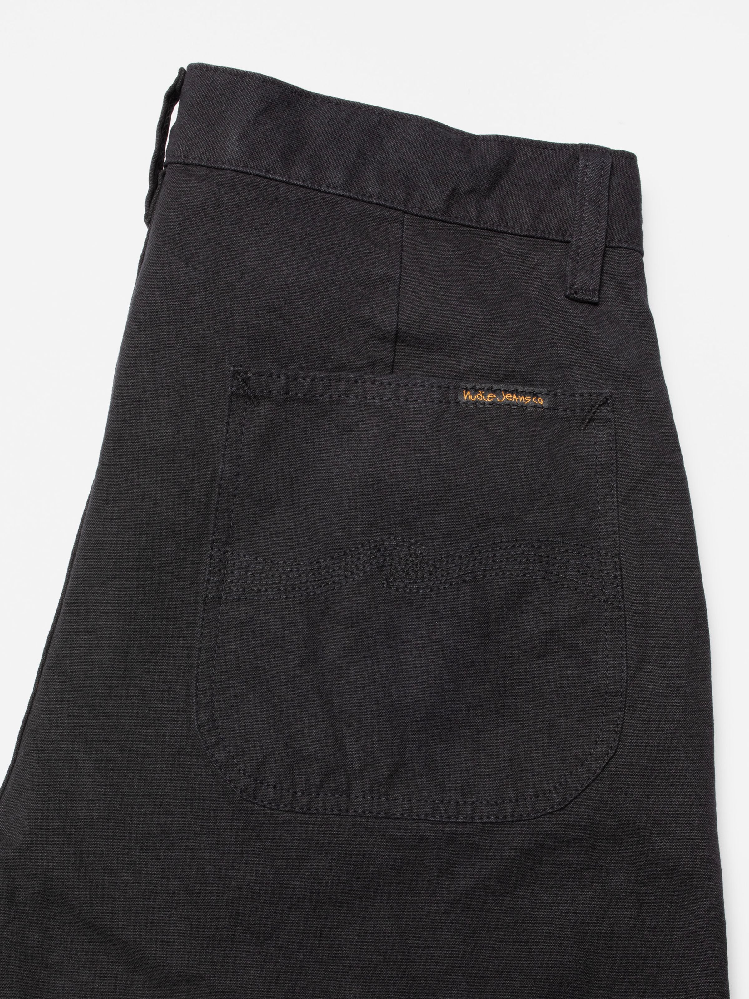 Nudie Jeans Tuff Tony black organic cotton duck canvas pants, featuring a close-up of the back pocket and signature waves.