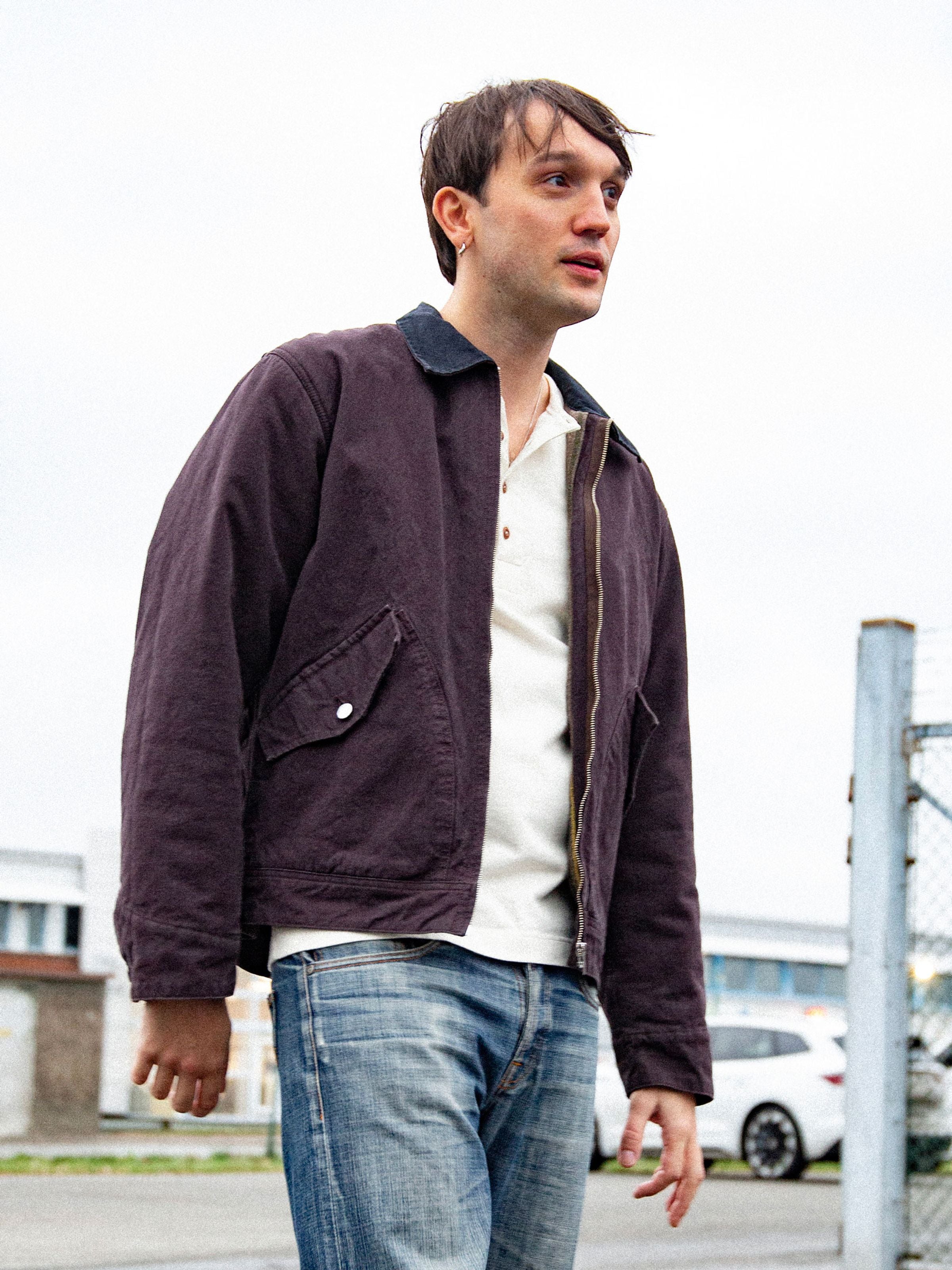 Nudie Jeans Blake Zip Jacket aus dunkelbraunem Bio-Baumwolle Duck Canvas mit schwarzem Kragen, am Model im Freien.