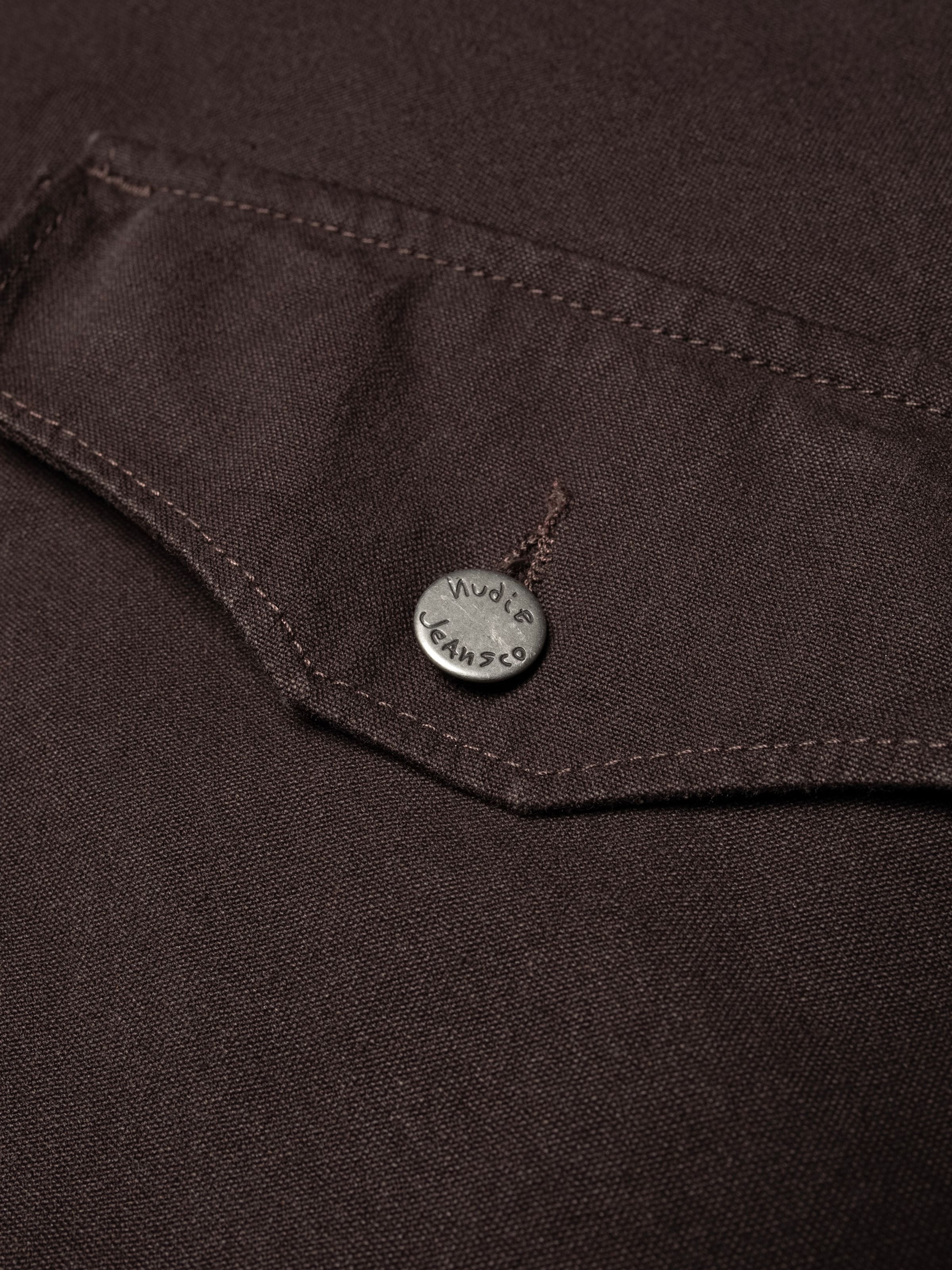 Nudie Jeans Blake Zip Jacket in Dark Brown aus Bio-Baumwolle Duck Canvas mit geschwungener Tasche und Logo-Metallknopf.