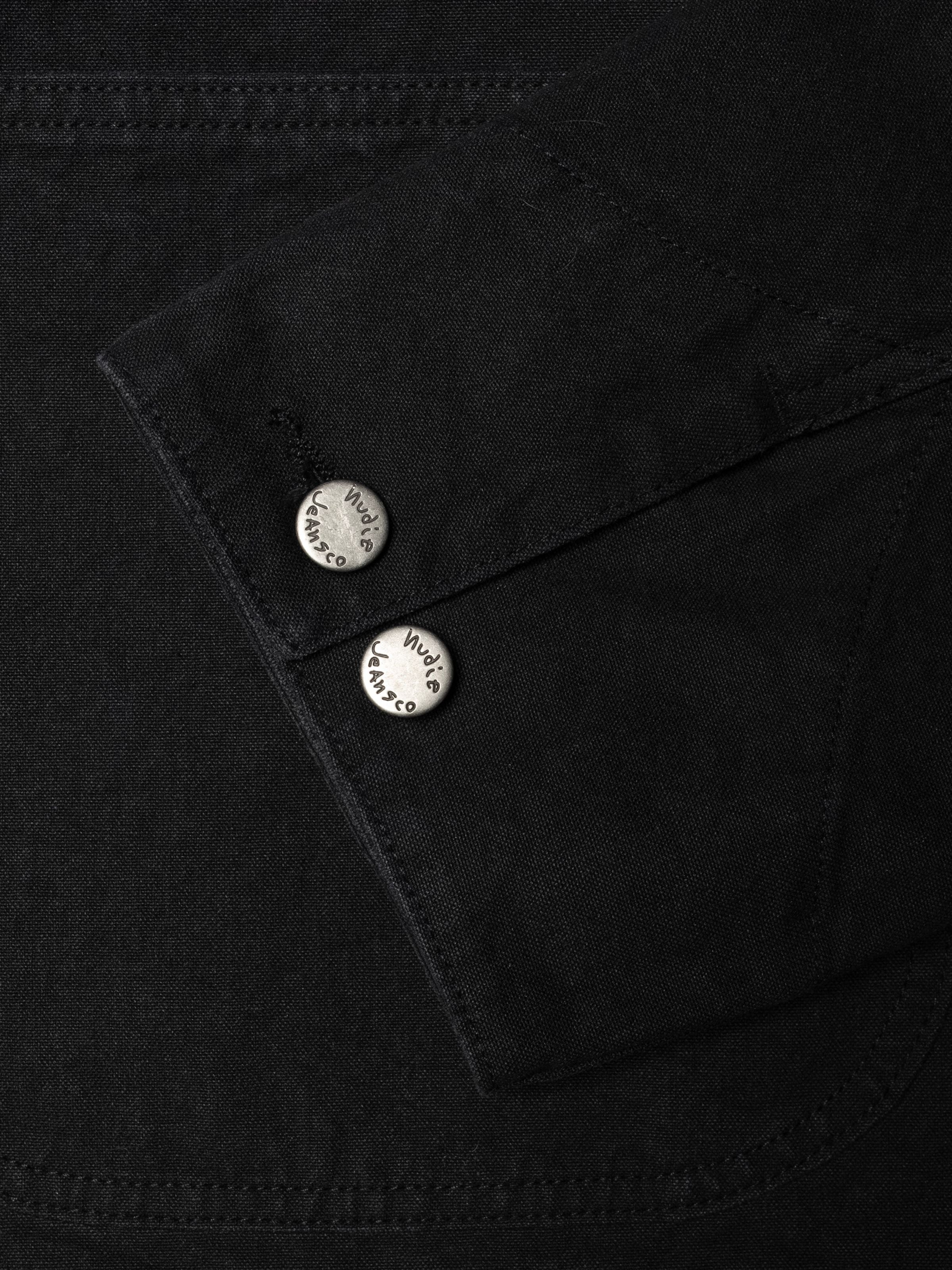 Nudie Jeans Howie Chore Jacket aus schwarzem Duck-Canvas aus Bio-Baumwolle, Nahaufnahme der antik-silbernen Knöpfe.