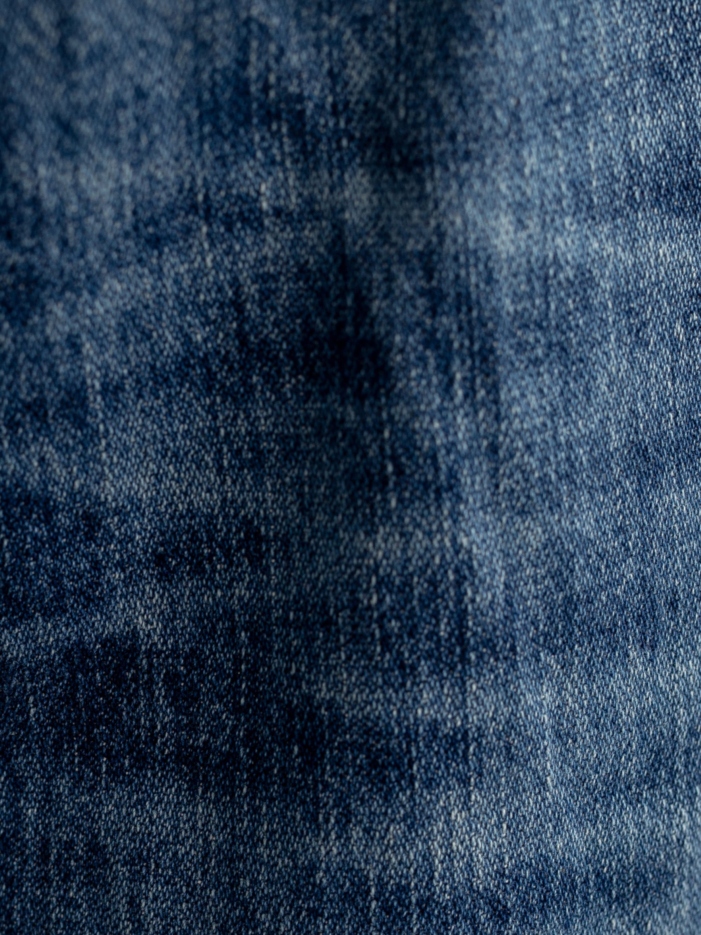 Nudie Jeans Loud Larry Muted Tracks, men's loose fit jeans, showing a close-up of the washed denim texture.