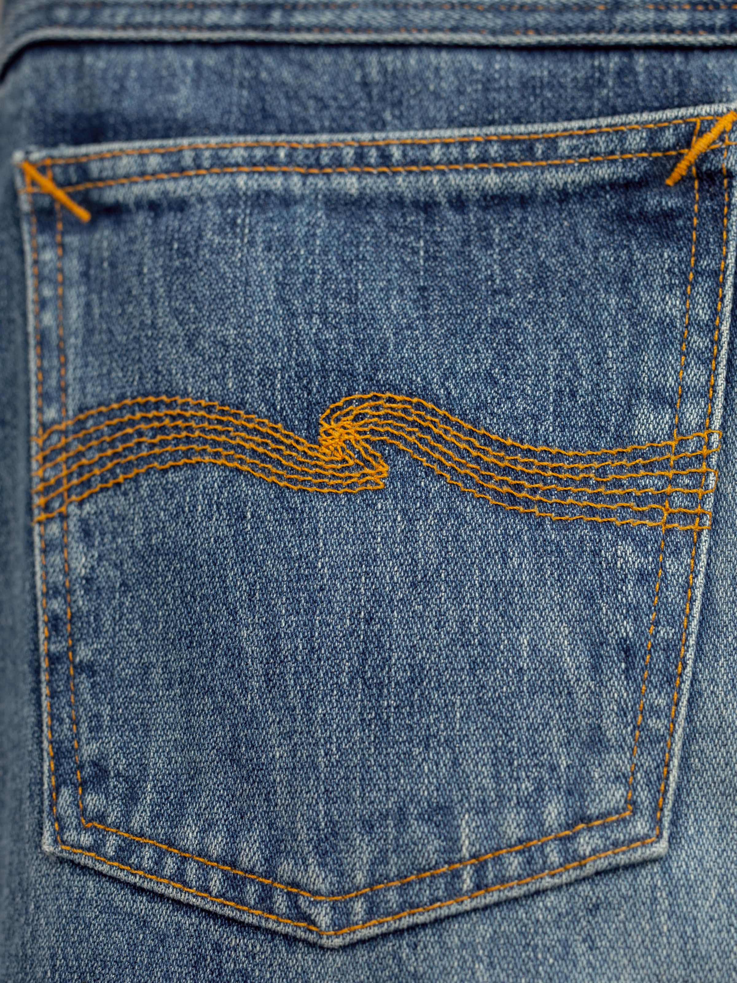 Nudie Jeans Loud Larry Muted Tracks, men's loose fit jeans, showing a close-up of the back pocket with signature embroidery.