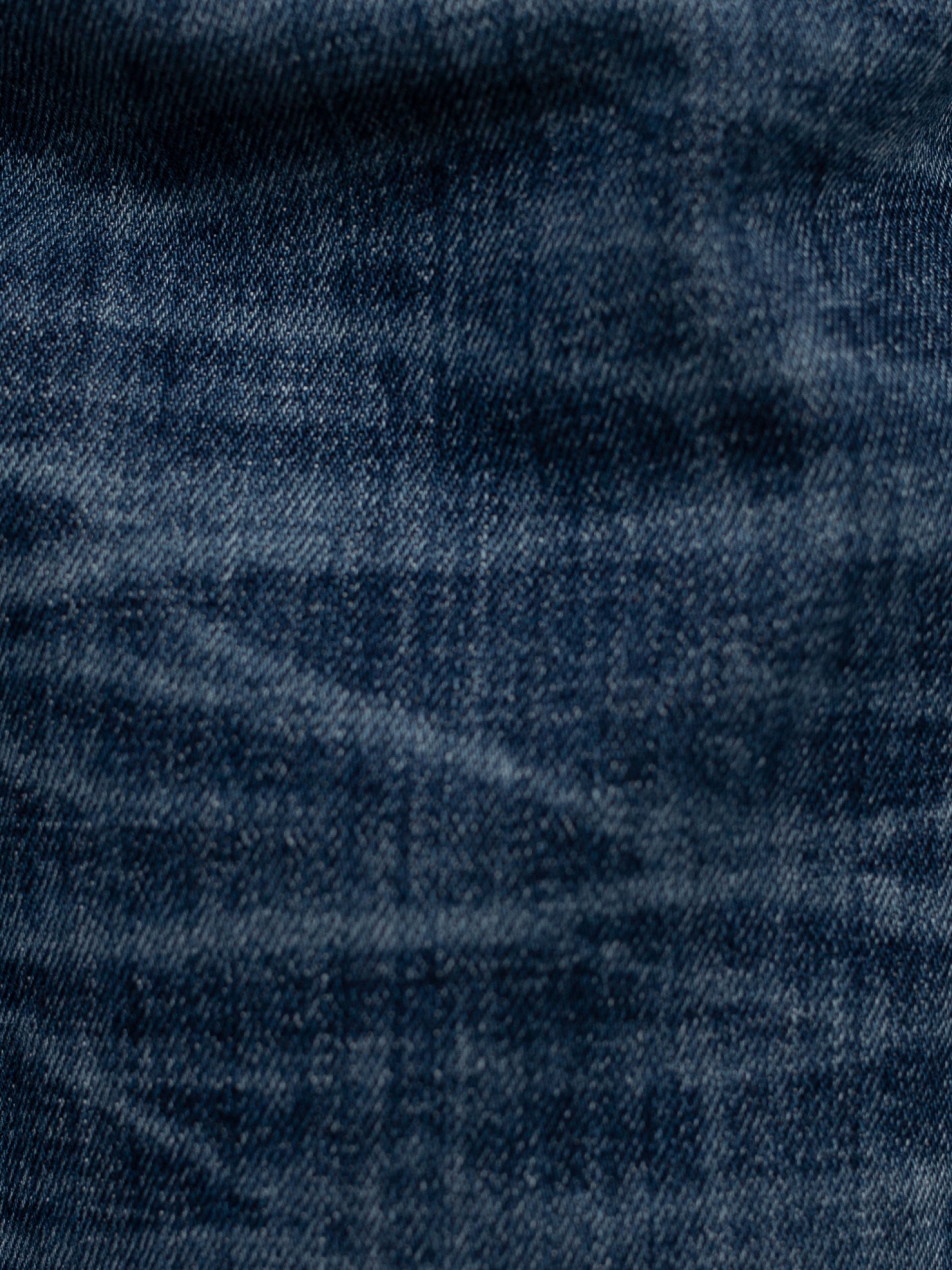 Nudie Jeans Solid Ollie Blue Echo Tracks, a close-up of the blue organic cotton comfort stretch denim with vertical streaks.