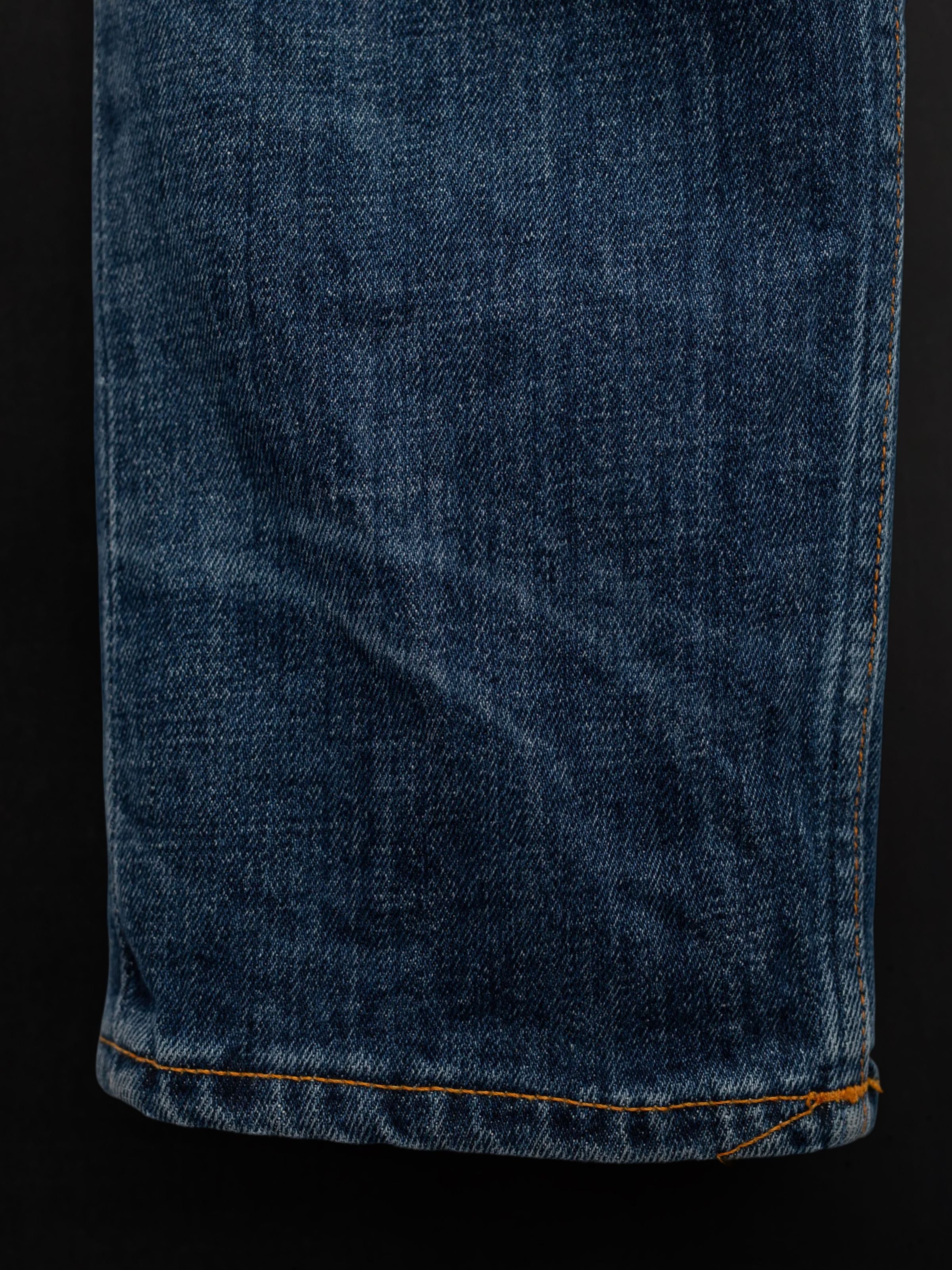Nudie Jeans Solid Ollie Blue Echo Tracks, a close-up of blue organic cotton comfort stretch denim with orange stitching.