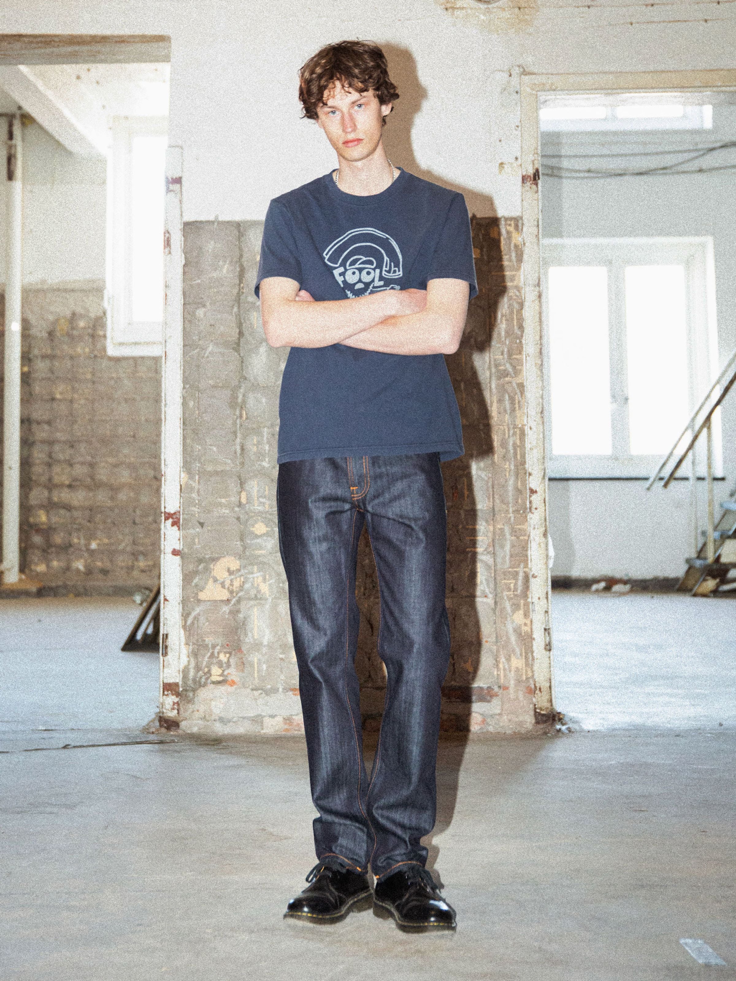 Nudie Jeans Gritty Jackson Blue Dry Two, men's regular fit jeans in dark indigo organic cotton rigid denim, worn by a model.