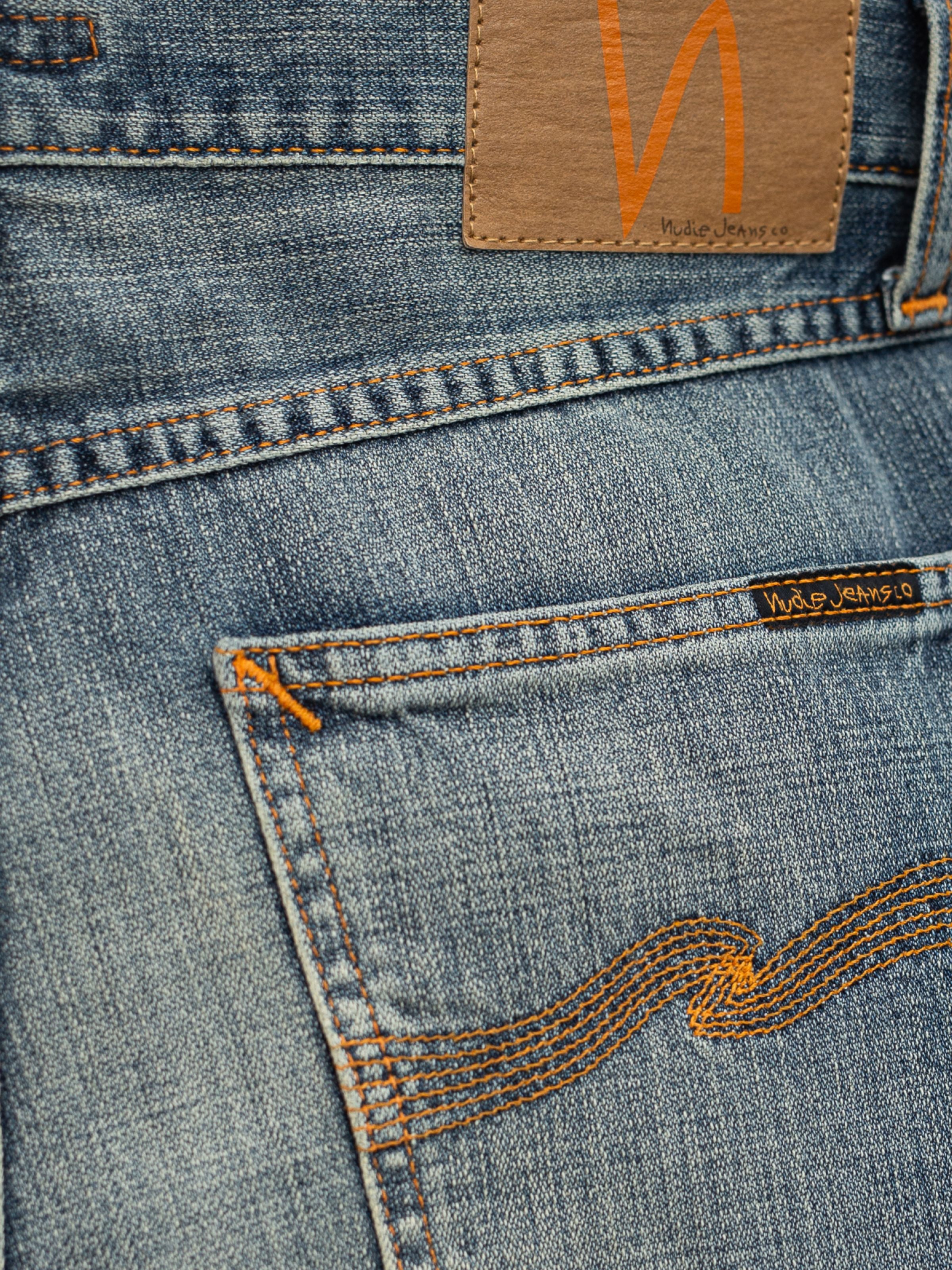 Nudie Jeans Rad Rufus Echoed Gold, close-up of the back pocket and orange thread on mid-blue rigid organic cotton denim.