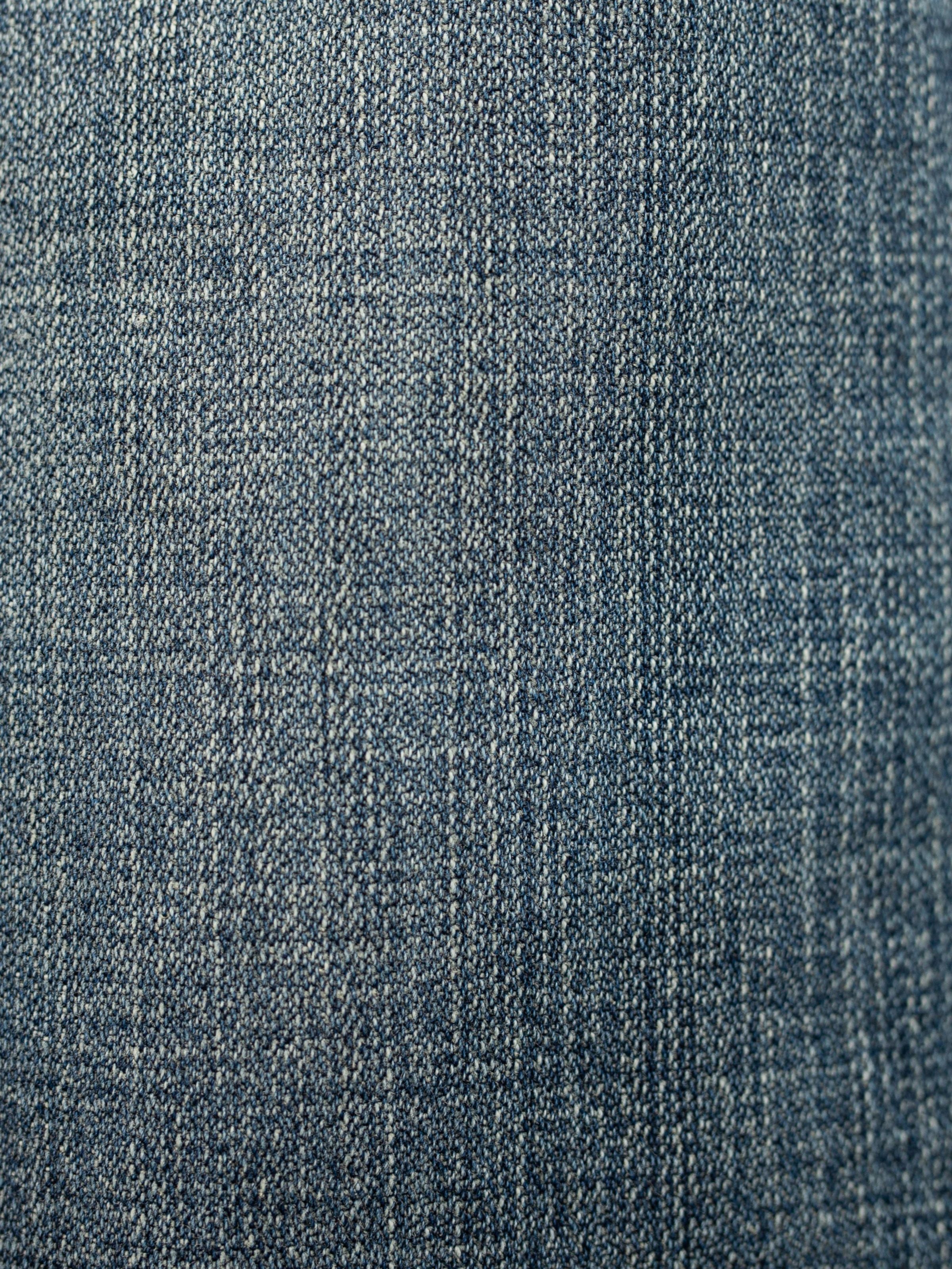 Nudie Jeans Rad Rufus Echoed Gold, a close-up of the mid blue organic cotton rigid broken twill denim fabric.