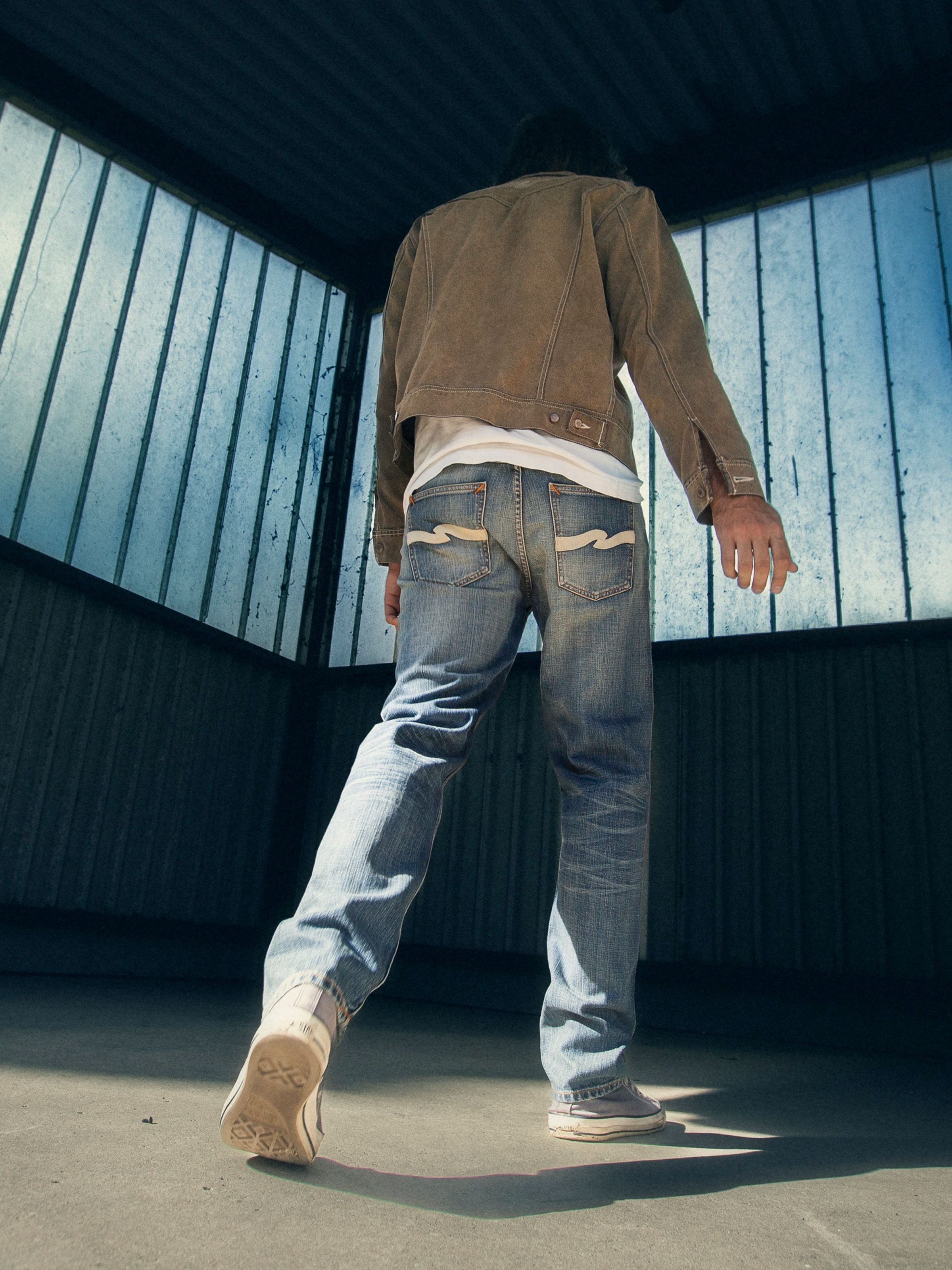 Nudie Jeans Gritty Jackson Tidal Waves, a model wearing regular fit jeans in a mid blue wash, shown from the back.