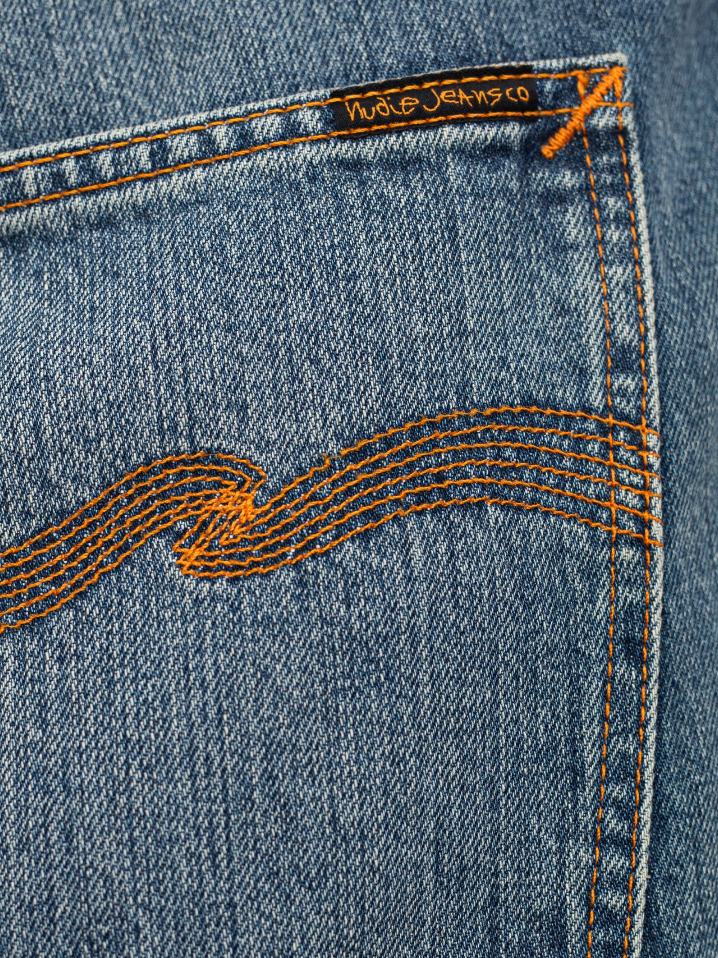 Nudie Jeans Tuff Tony Quiet Gold, a close-up of the orange back pocket embroidery on mid blue organic cotton rigid denim.