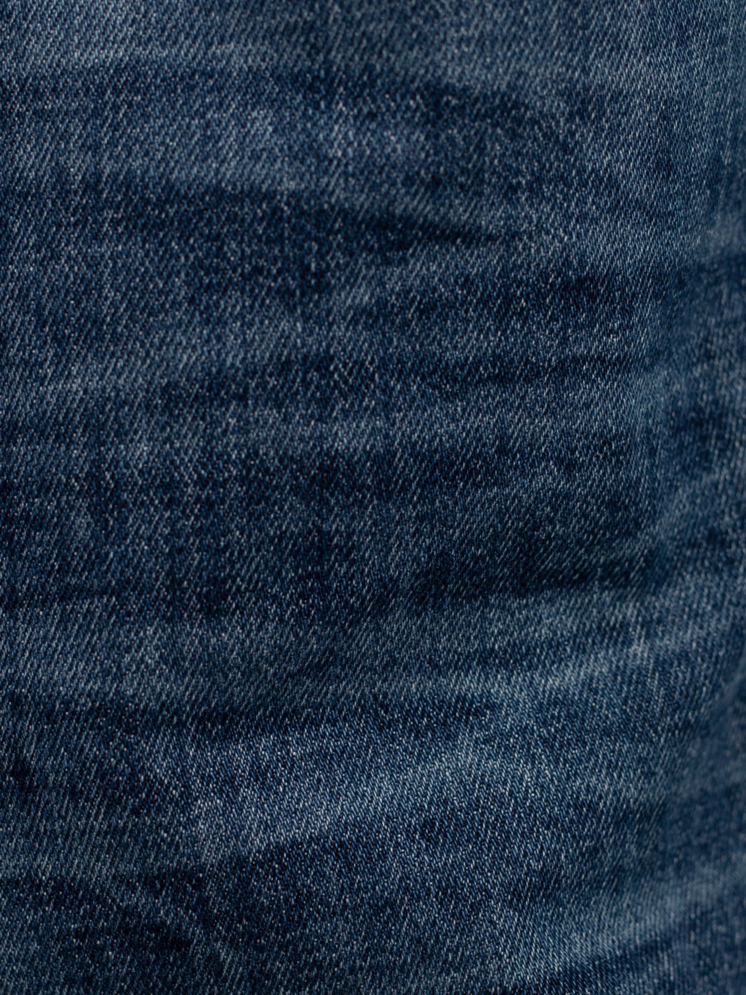 Nudie Jeans Lean Dean Echo Tracks, a close-up of the dark blue washed organic cotton comfort stretch denim fabric.