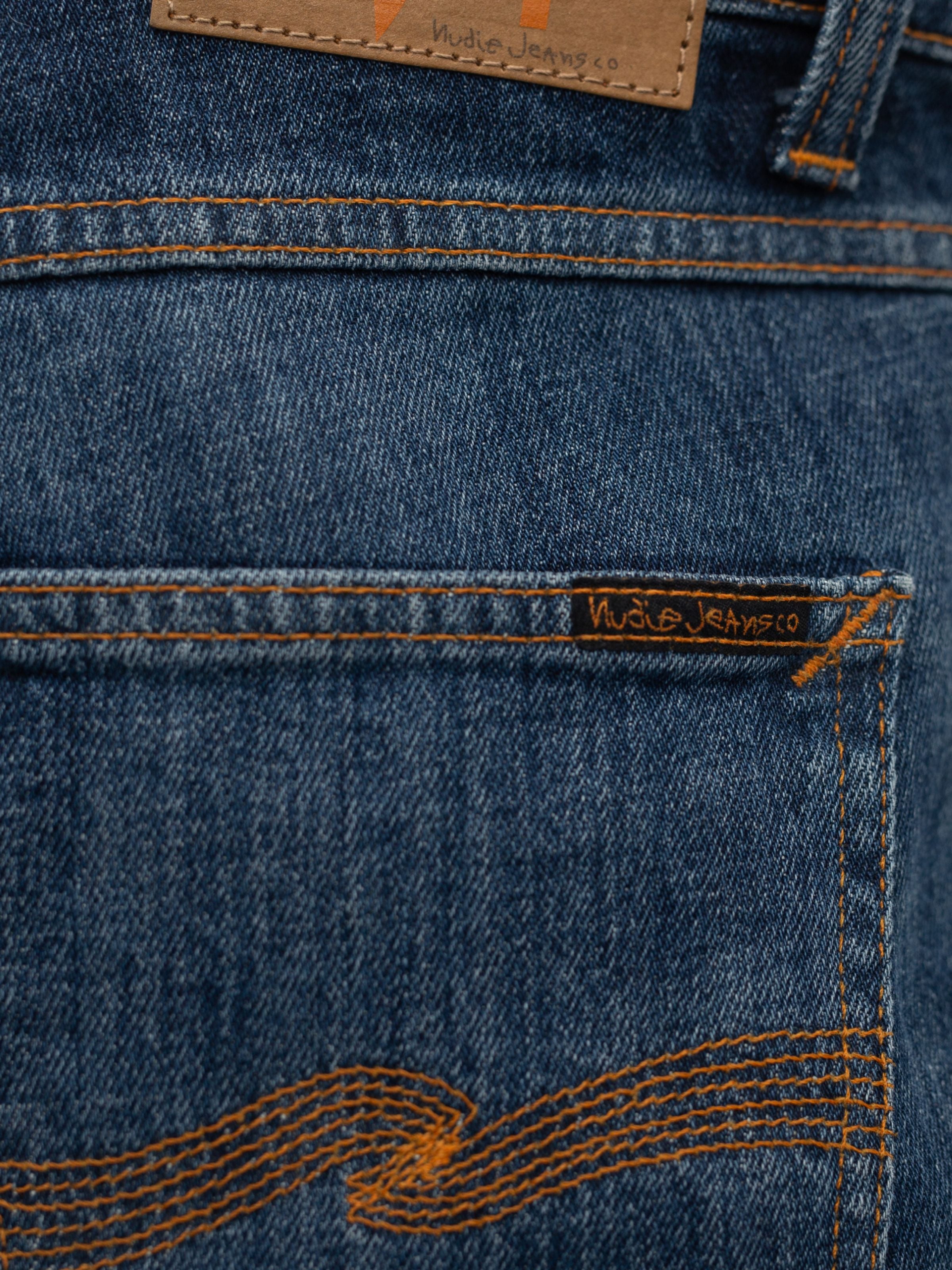 Nudie Jeans Lean Dean Echo Tracks, showing the back pocket label and orange stitching on washed organic cotton denim.