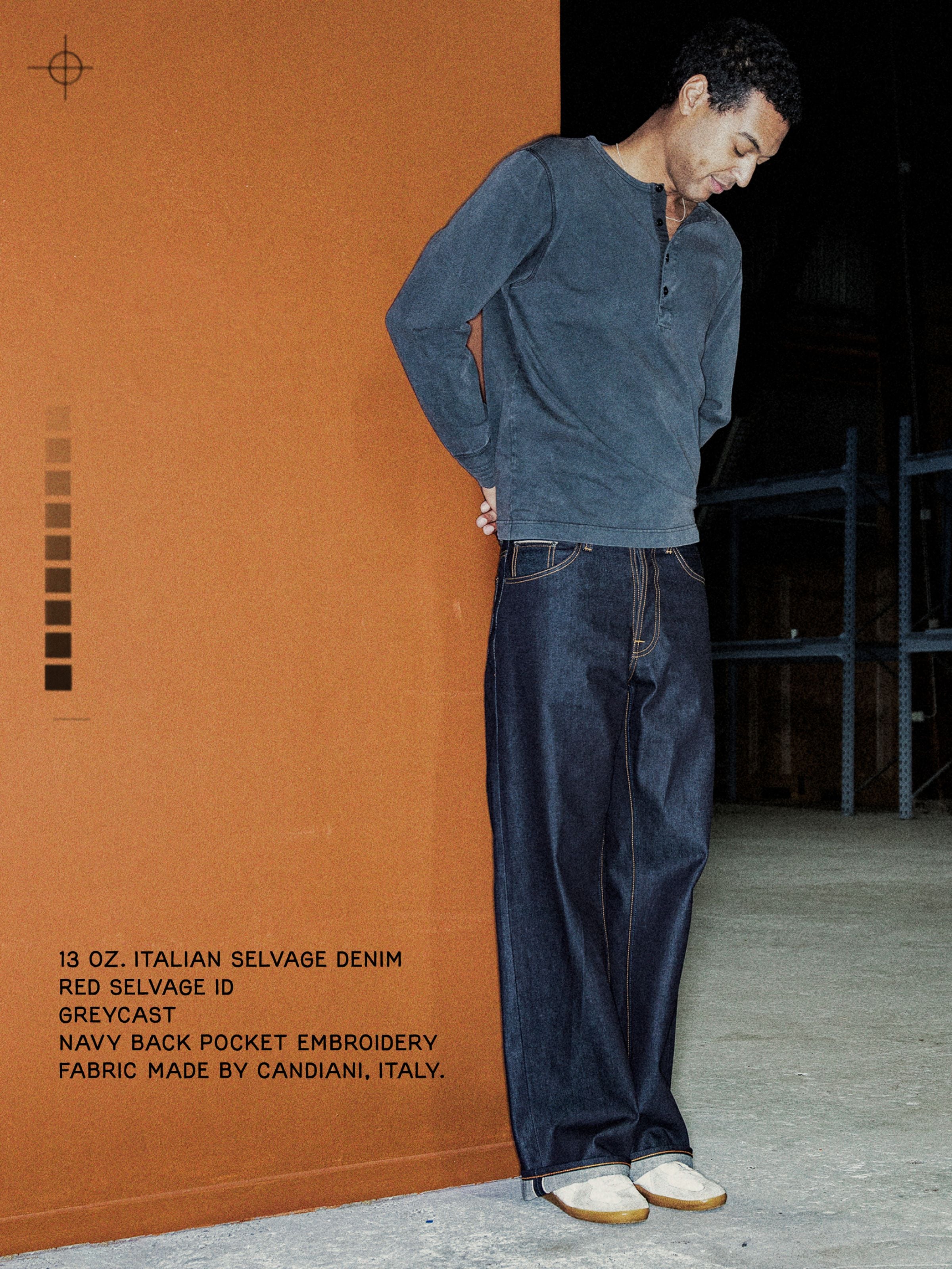 Nudie Jeans Loud Larry Lightning Selvage, Herrenjeans mit lockerer Passform, vor einer orangen Wand.