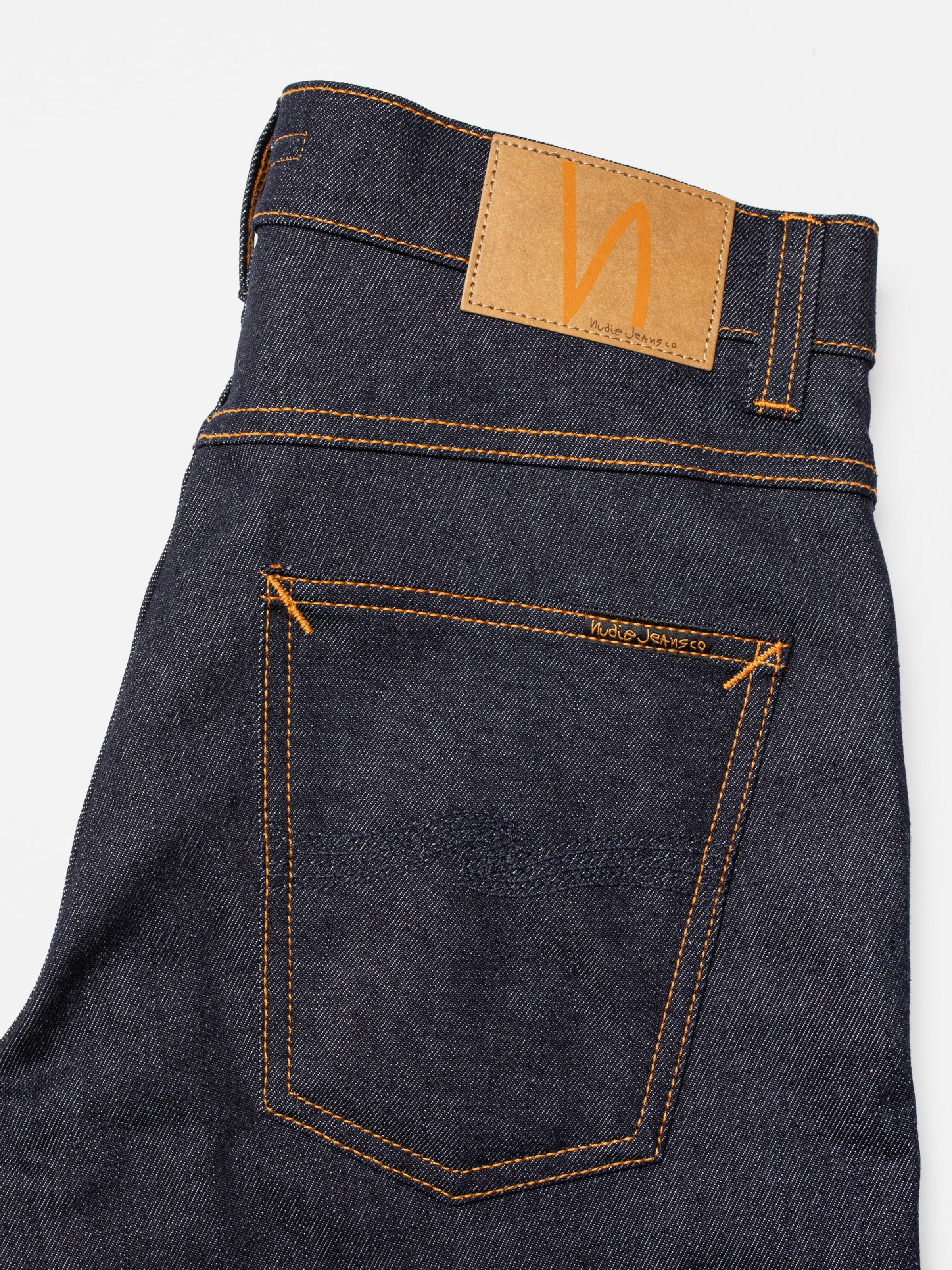 Nudie Jeans Grim Tim Dry Blue 16 Dips, close-up of the back pocket showing orange stitching and the tan Jacron patch.