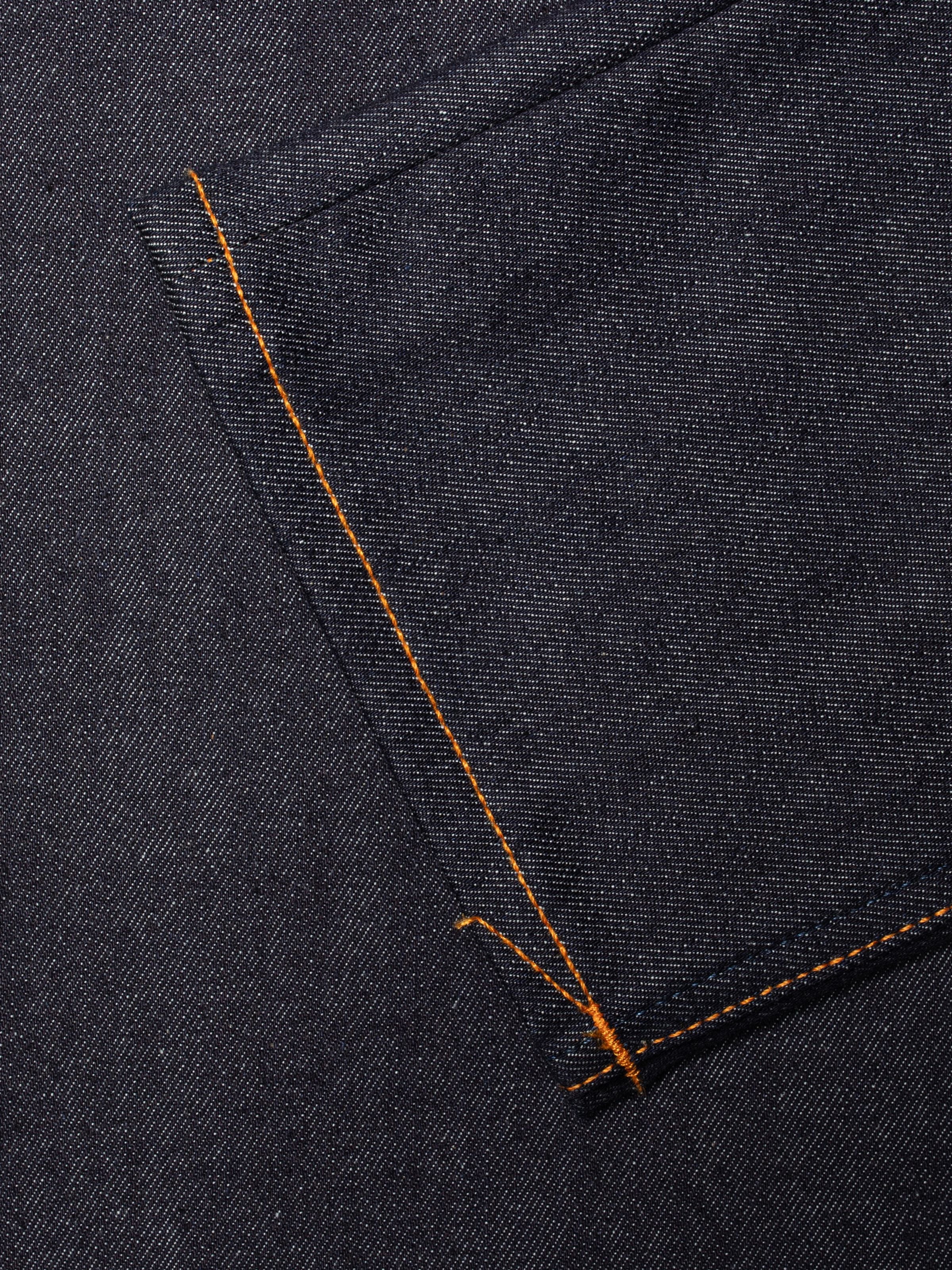 Nudie Jeans Grim Tim Dry Blue 16 Dips, close-up of the dark blue organic cotton denim with orange topstitching.