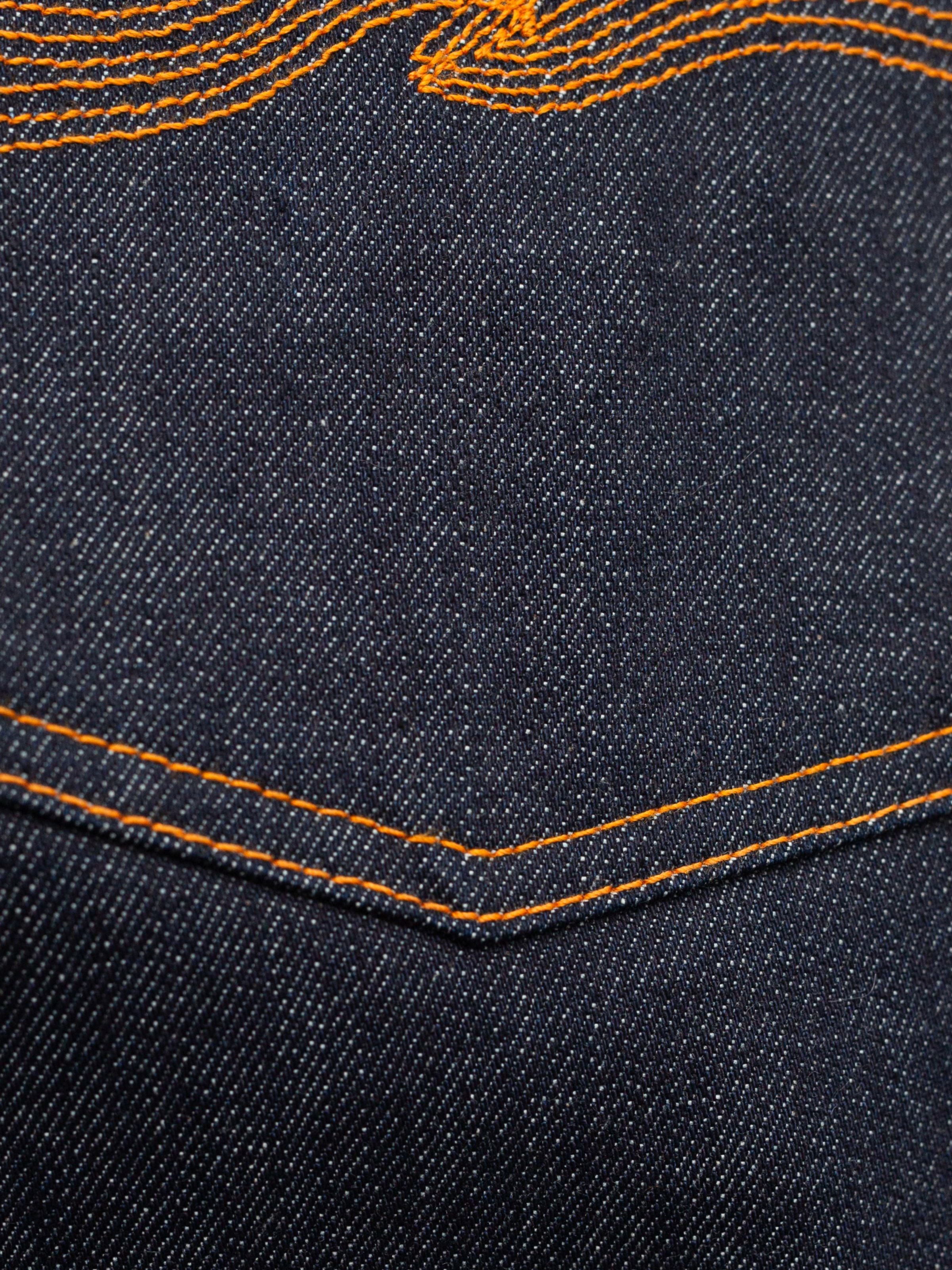 Nudie Jeans Steady Eddie II Dry One, Nahaufnahme des Indigo Rigid Denim aus Bio-Baumwolle und orangefarbenen Nähten.