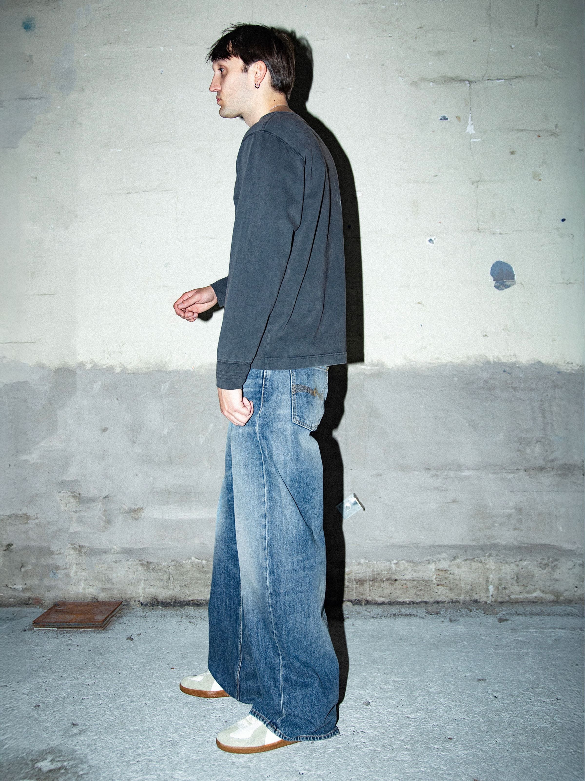 Nudie Jeans Loud Larry Gravel Stone, mid-blue wide-leg jeans in organic cotton, shown from the side on a model.