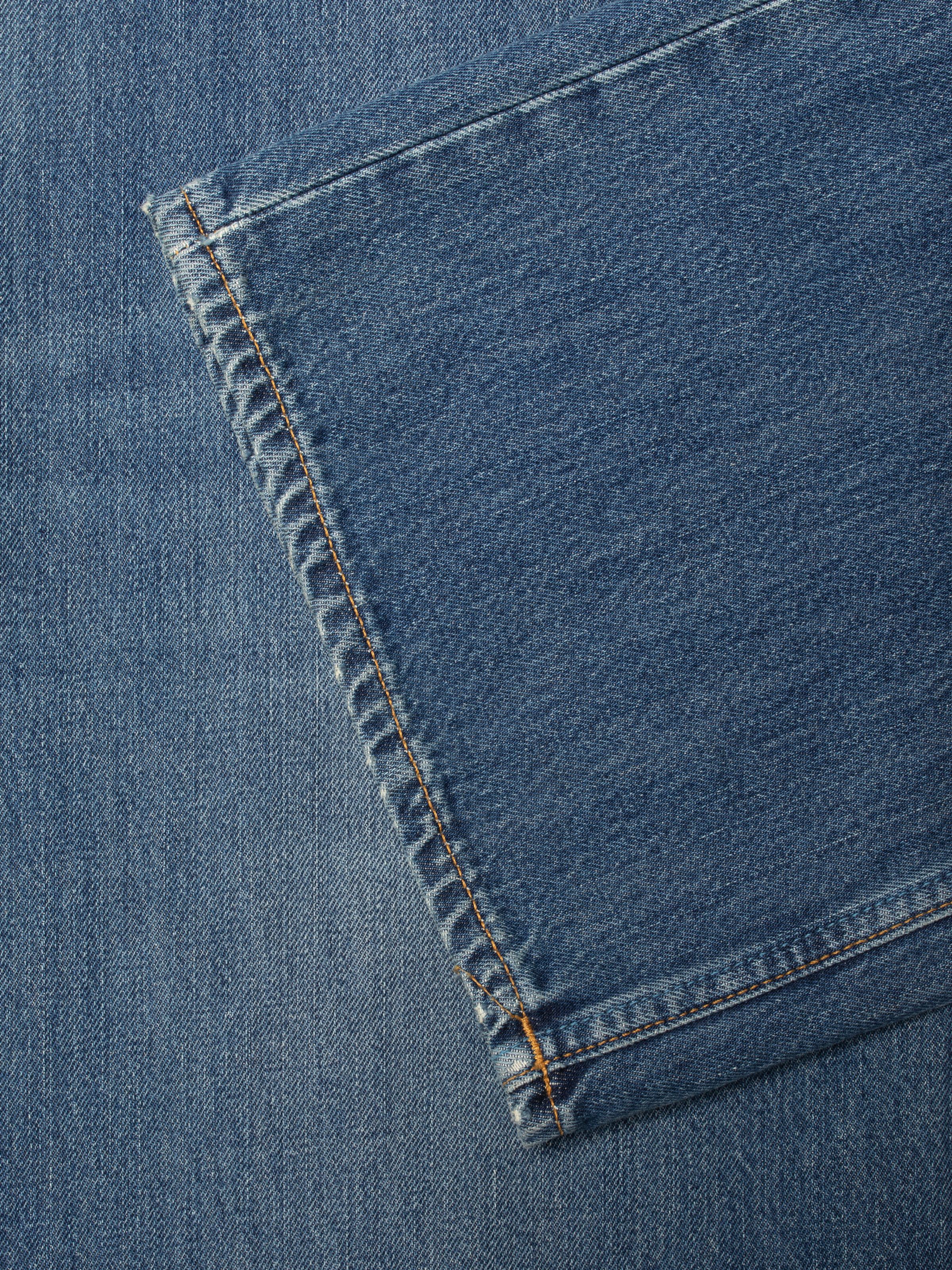 Nudie Jeans Loud Larry Gravel Stone, close-up of the mid-blue organic cotton denim showing tobacco thread seams.