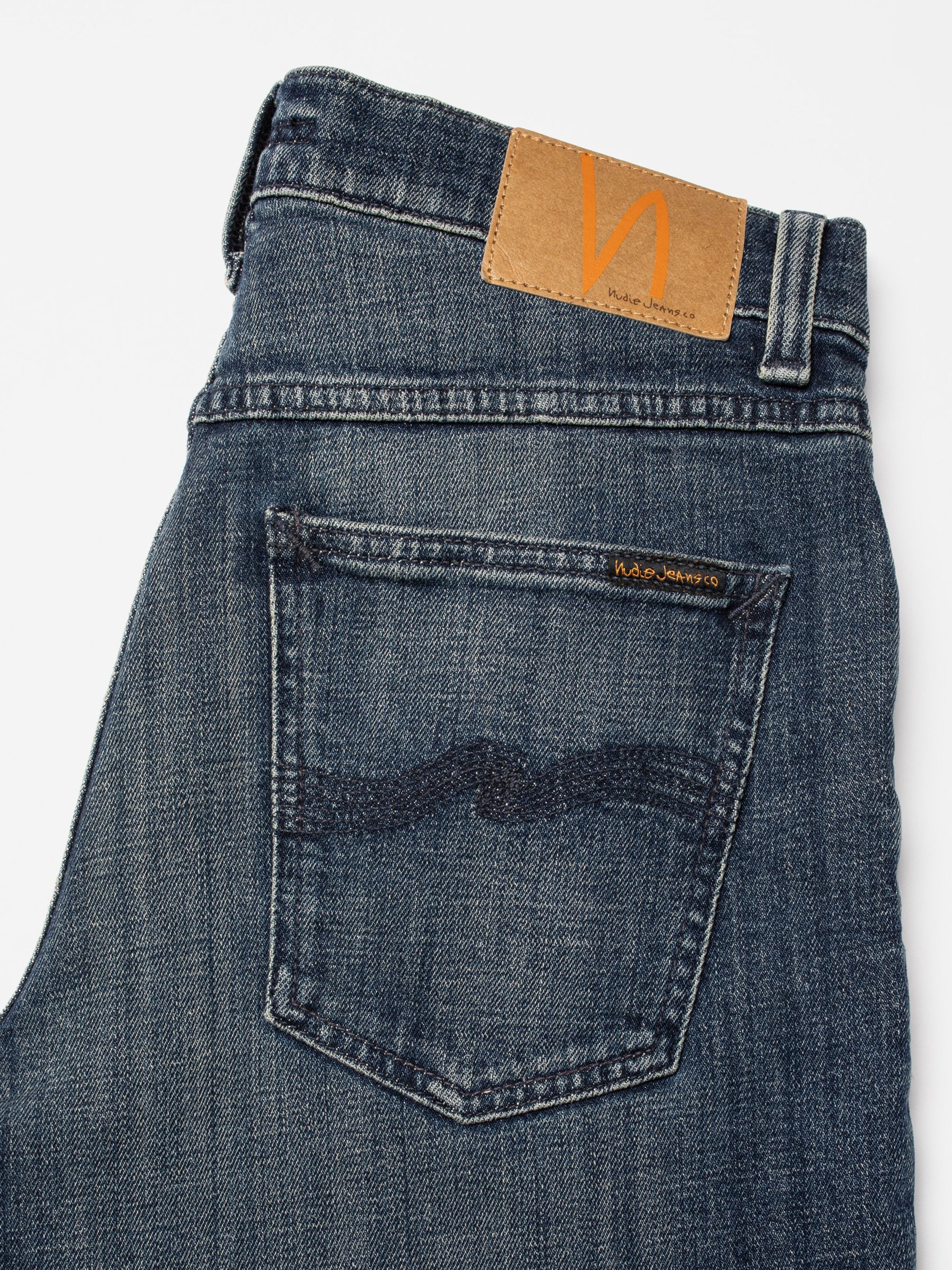 Nudie Jeans Solid Ollie Epic Ink, close-up of the back pocket and Jacron patch on dark blue organic cotton denim.