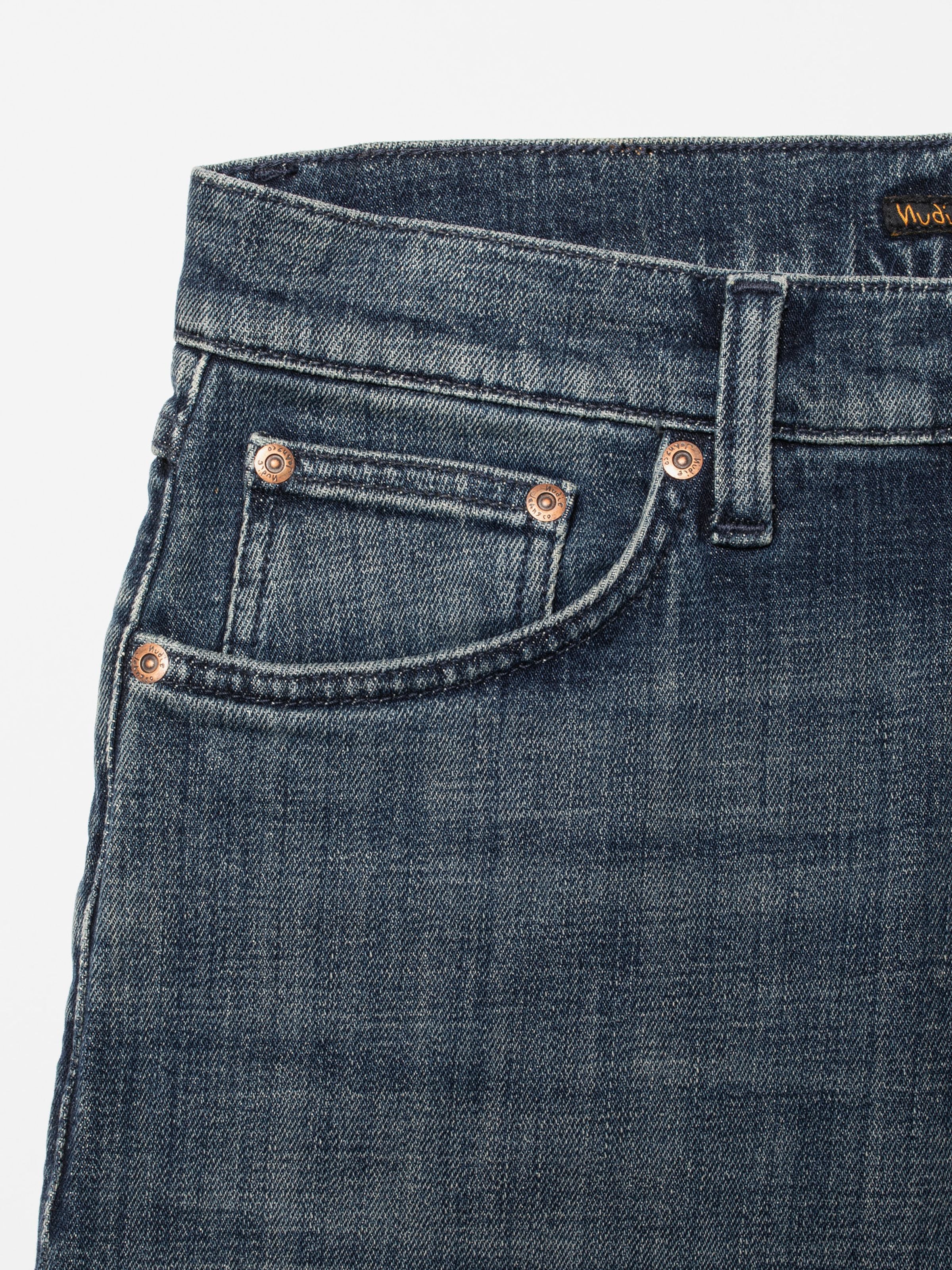 Nudie Jeans Solid Ollie Epic Ink, close-up of the front pocket and copper rivets on dark blue organic cotton denim.