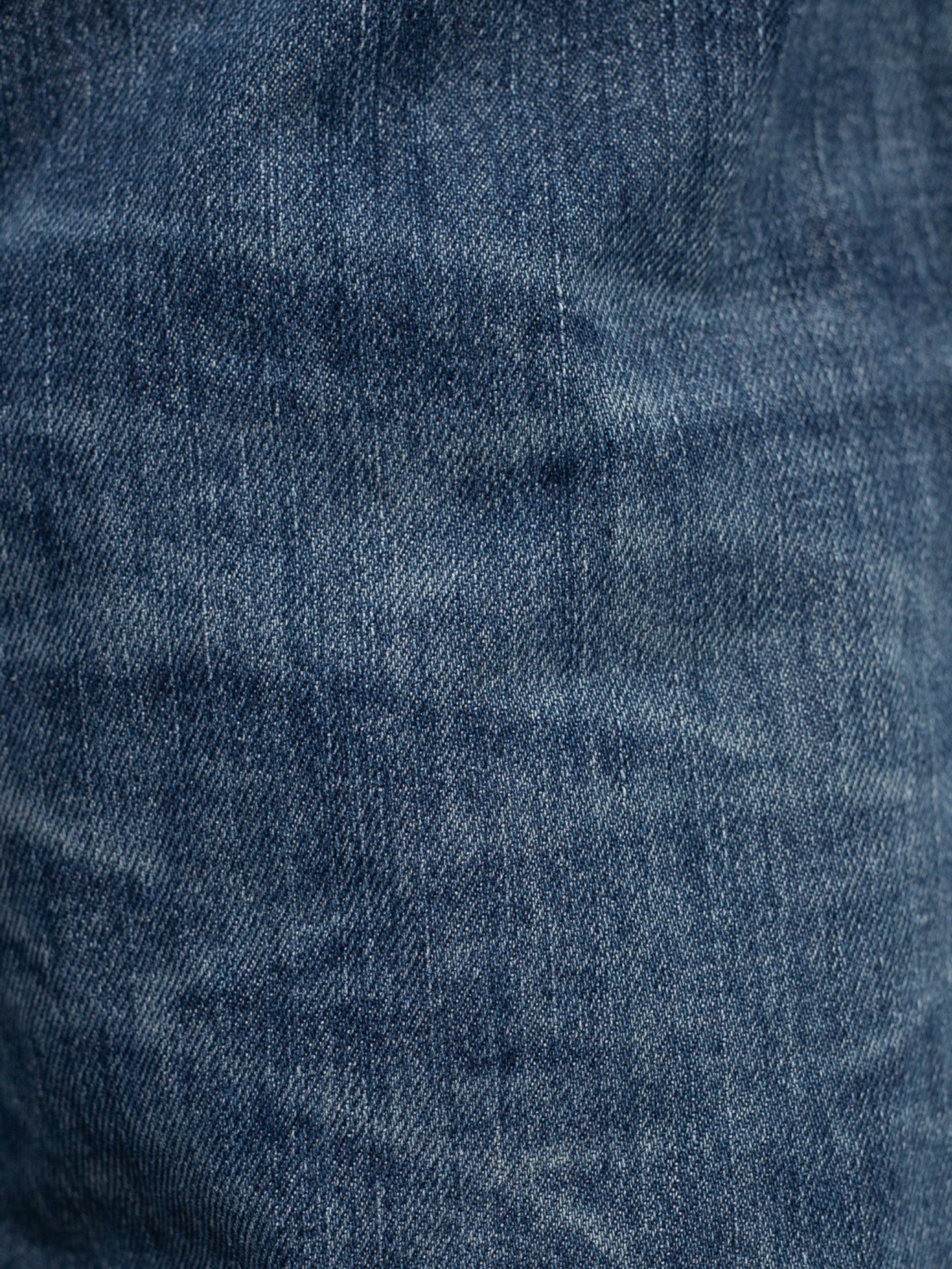 Nudie Jeans Rad Rufus Blue Twisted Tracks, a close-up of the washed indigo blue rigid organic cotton denim fabric.