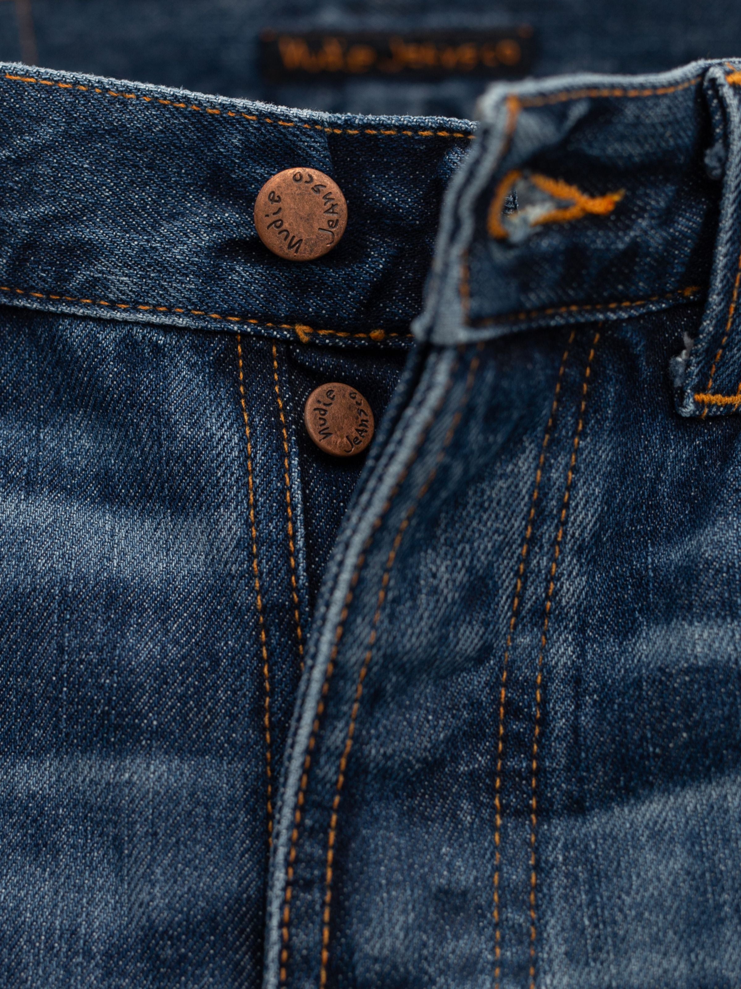 Nudie Jeans Rad Rufus Blue Twisted Tracks, a close-up of the copper button fly on blue organic cotton rigid denim.