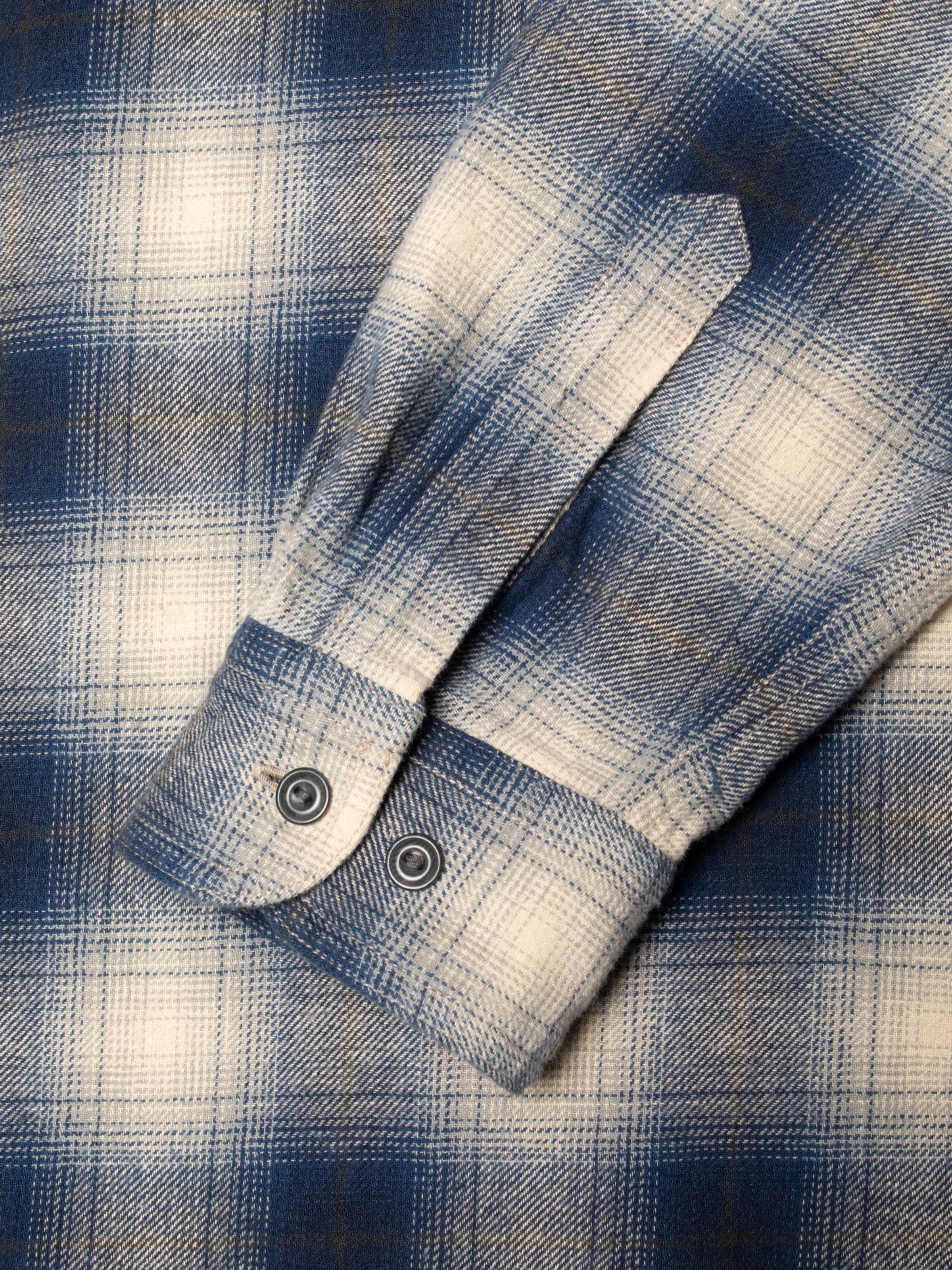 Nudie Jeans Julian Worker Shirt Checked Blue, close-up of the buttoned sleeve cuff on checked organic cotton fabric.