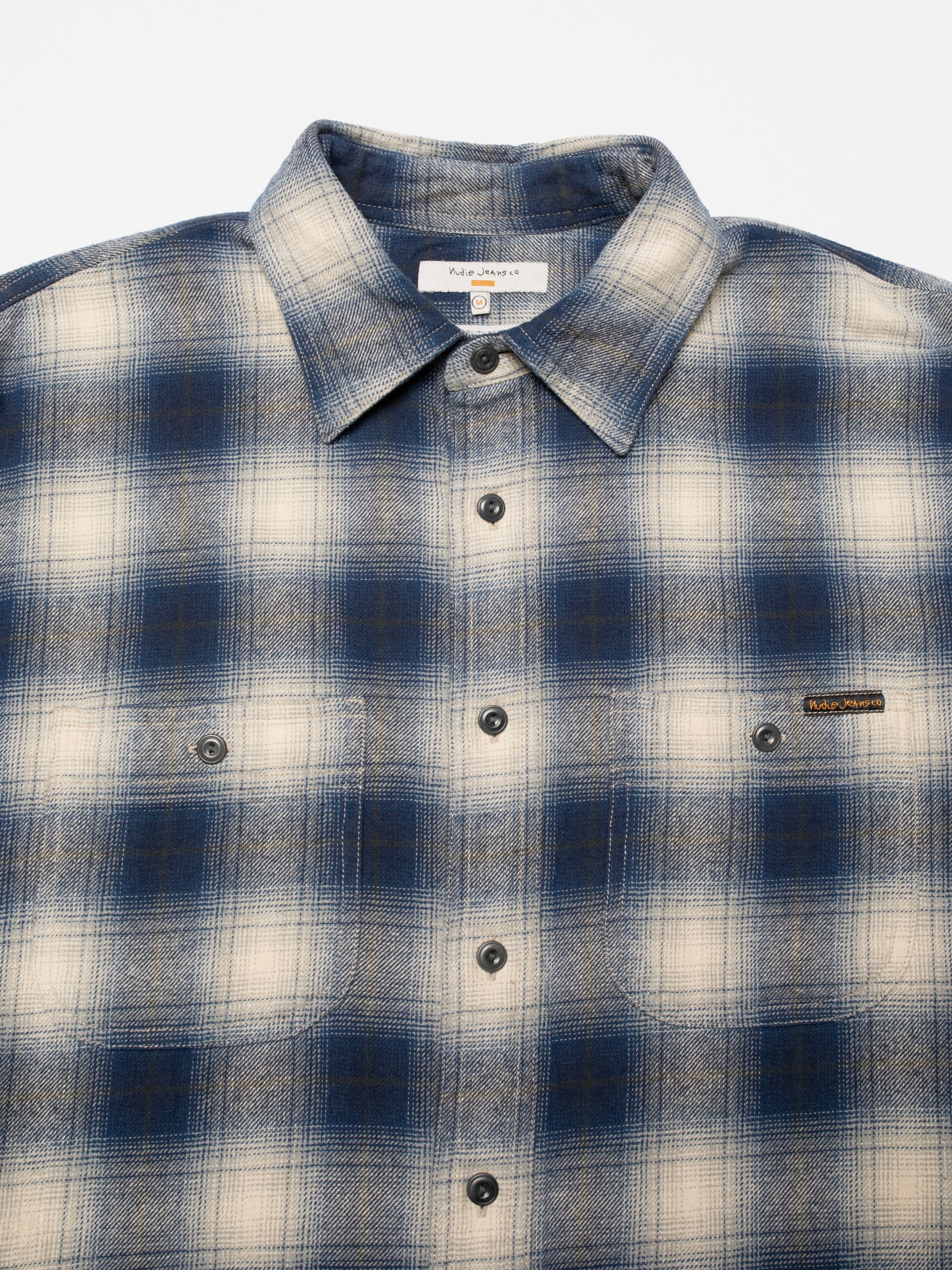 Nudie Jeans Julian Worker Shirt Checked Blue, close-up of the collar and chest pockets on the blue organic cotton shirt.
