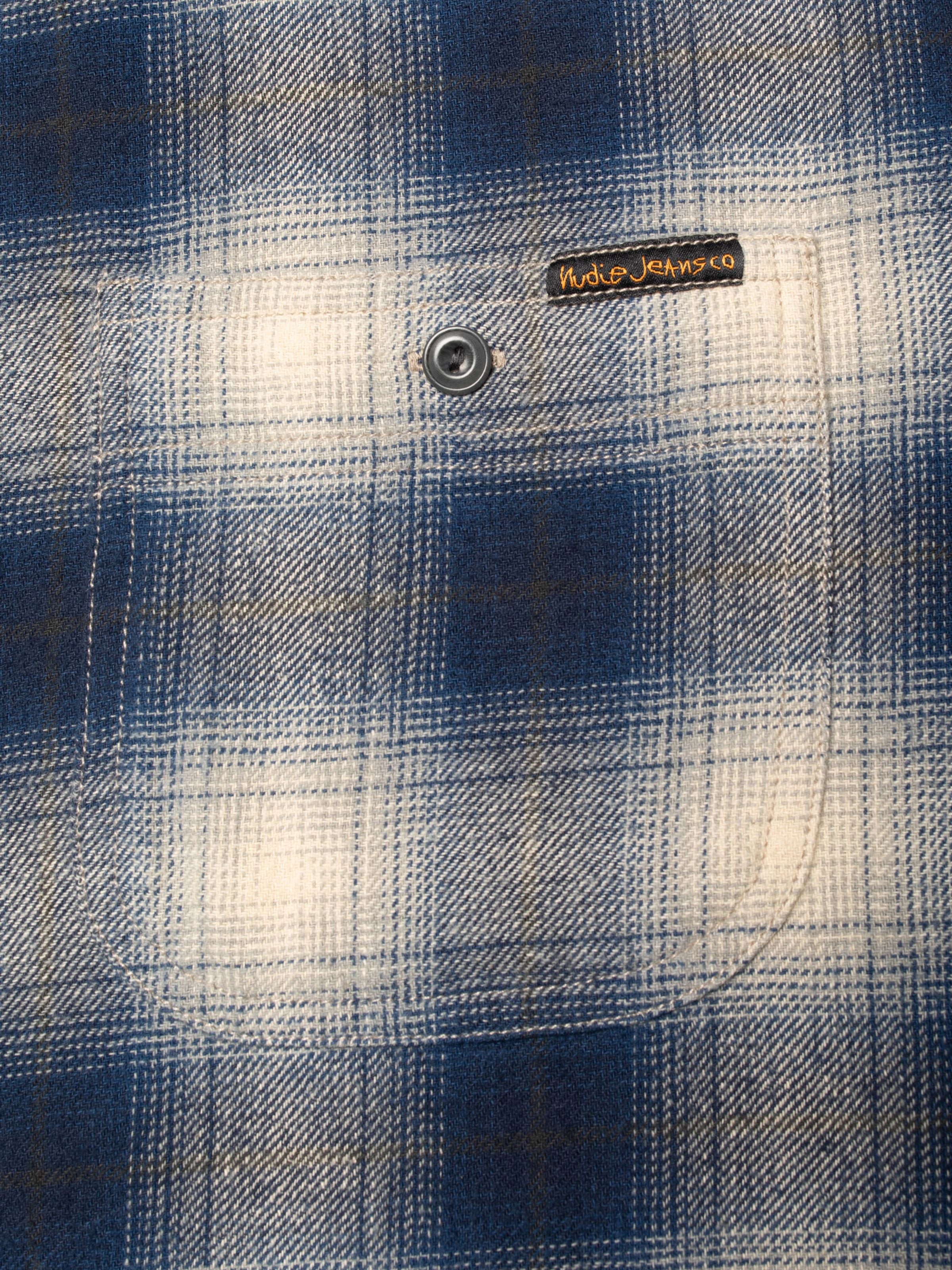 Nudie Jeans Julian Worker Shirt Checked Blue, close-up detail of the organic cotton chest pocket and brand label.