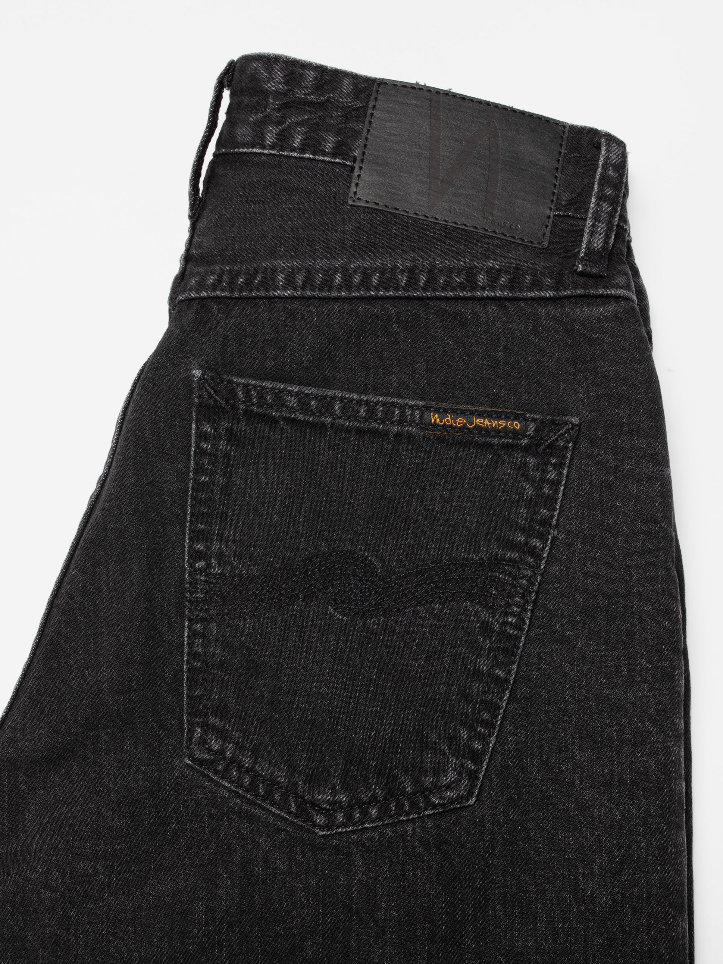 Nudie Jeans Breezy Britt Friendly Black, close-up of the back pocket and black Jacron patch on organic cotton rigid denim.