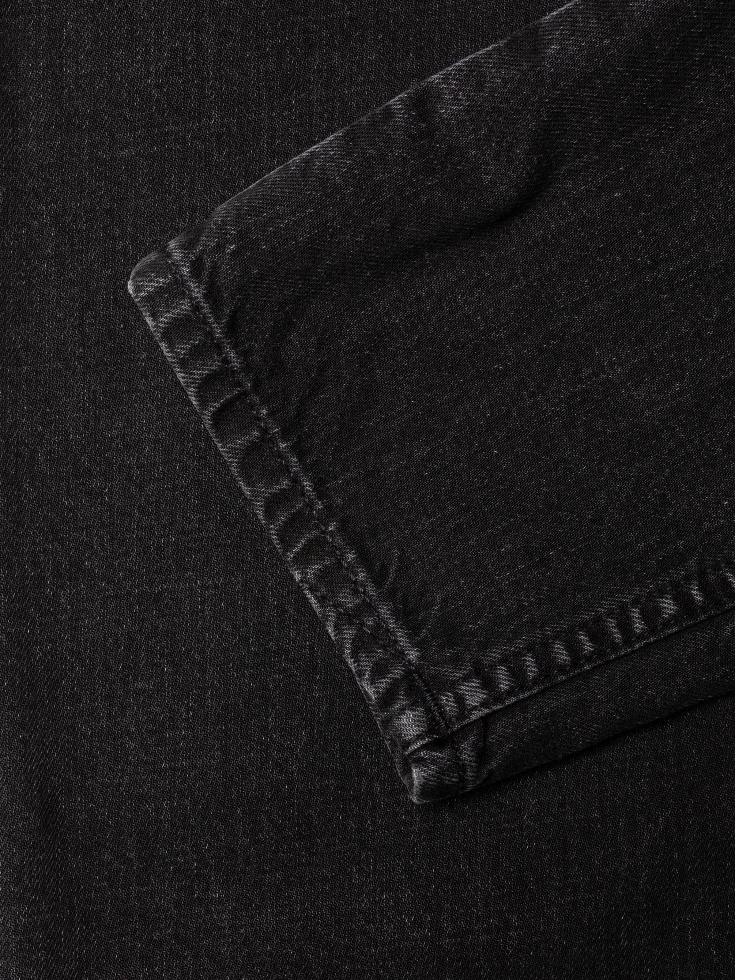 Nudie Jeans Breezy Britt Friendly Black, close-up of the leg opening on washed dark grey organic cotton rigid denim.