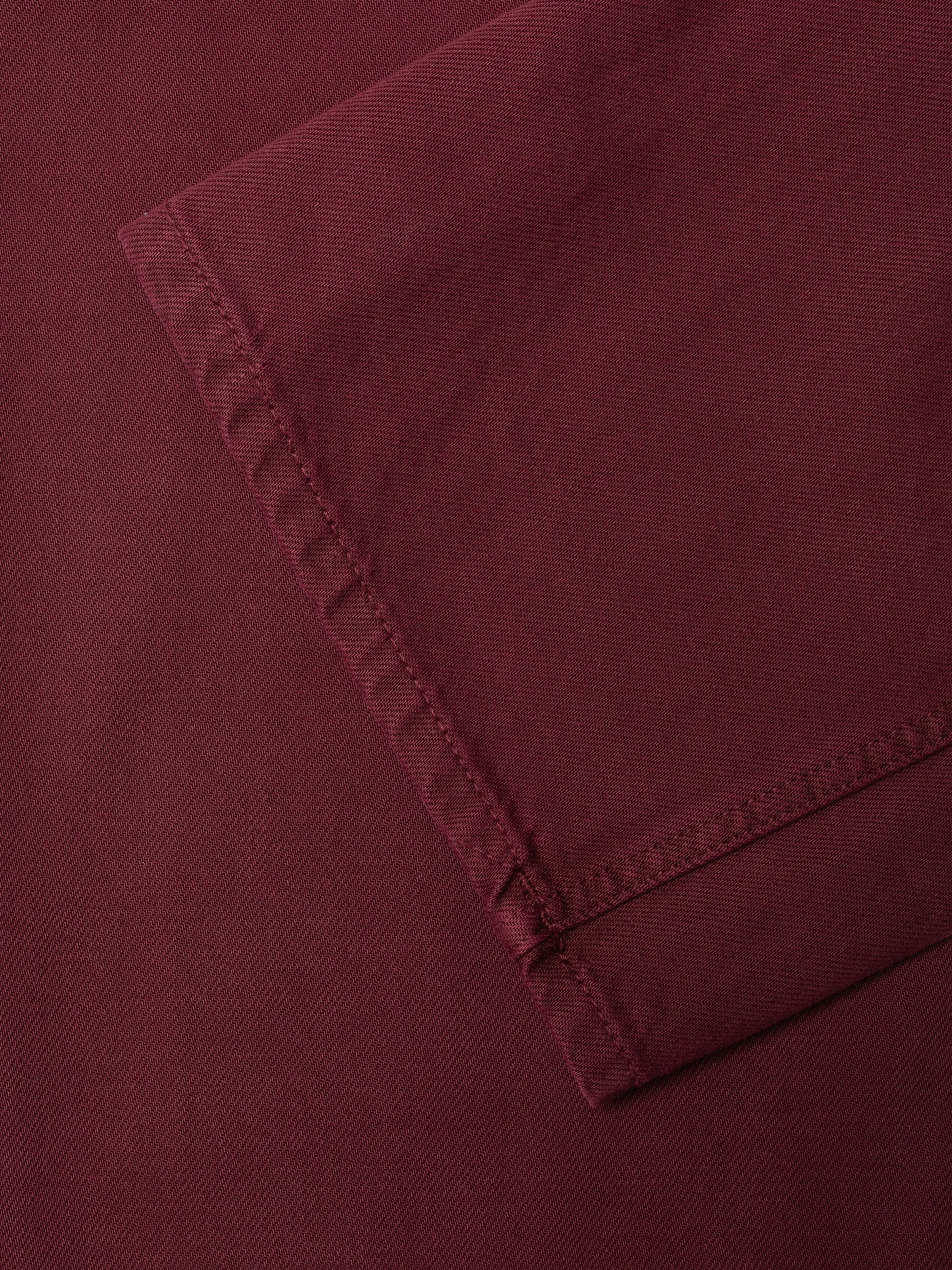 Nudie Jeans Clean Eileen Burgundy, close-up of the wide leg opening on rigid organic cotton denim in deep burgundy.