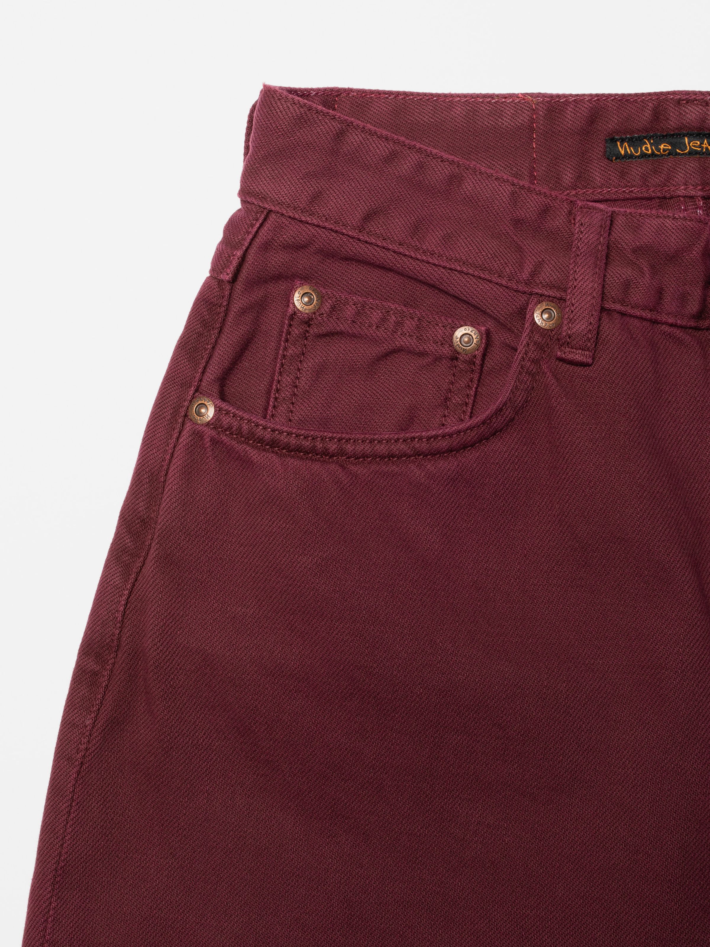 Nudie Jeans Clean Eileen Burgundy, close-up of the front pocket on rigid organic cotton denim with copper rivets.