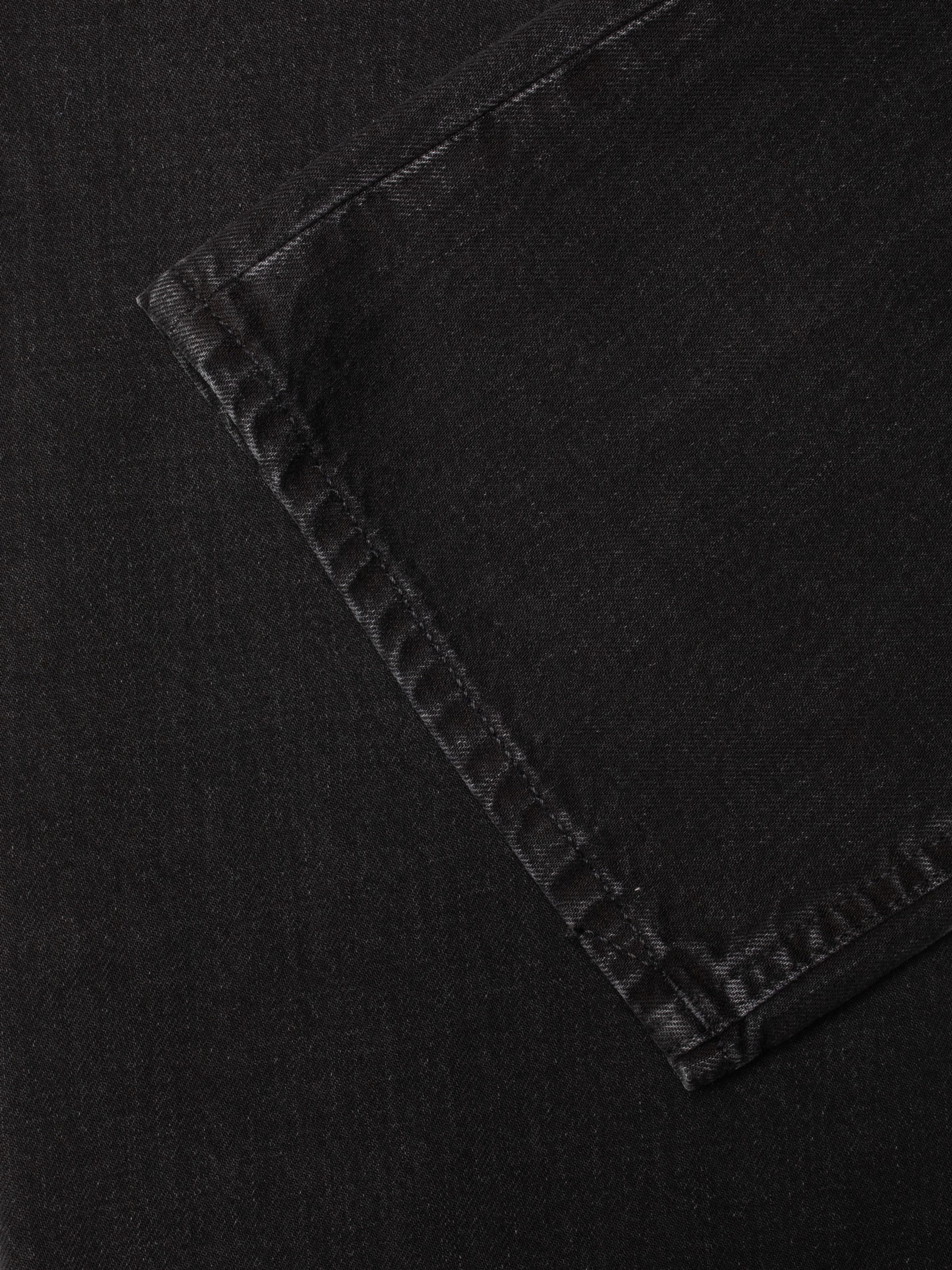 Nudie Jeans Clean Eileen Night Dune, close-up of the wide leg opening hem on washed organic cotton rigid black denim.