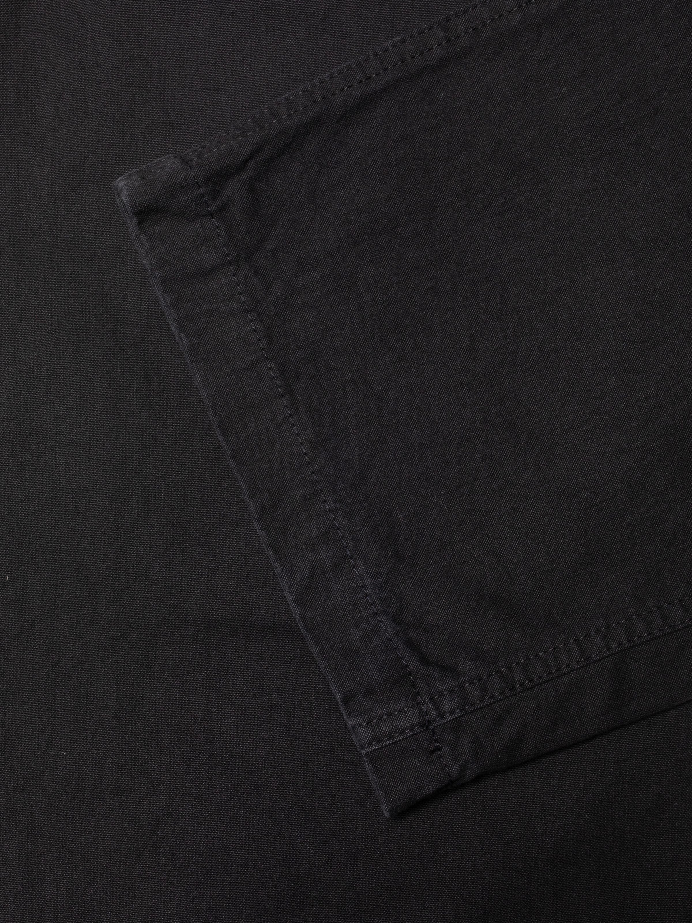 Nudie Jeans Wendy Pants aus schwarzem Duck Canvas, Nahaufnahme der Textur aus Bio-Baumwolle und der Nähte.