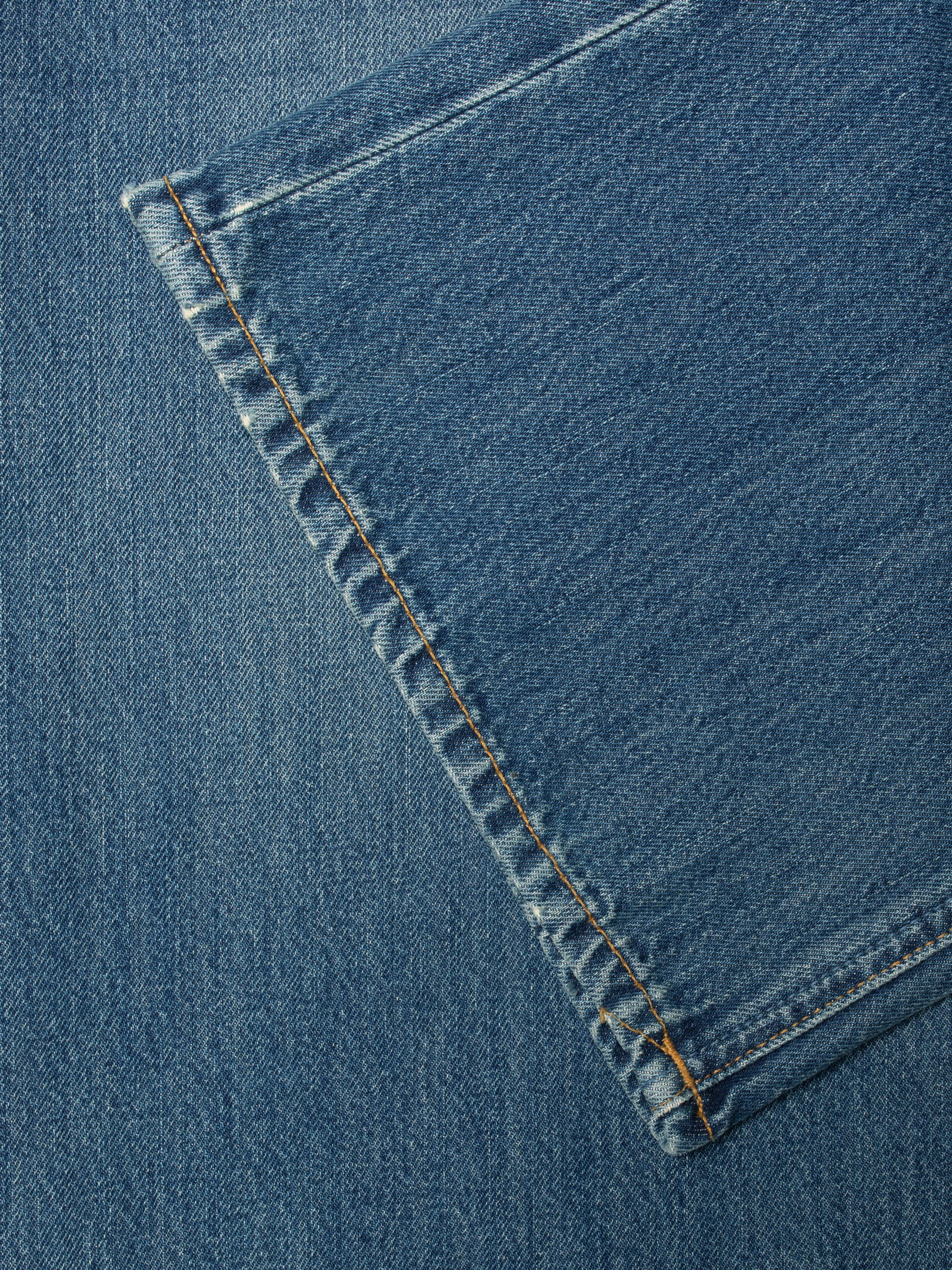 Nudie Jeans Wide Heidi Gravel Stone jeans, close-up of tobacco stitching on organic cotton rigid denim in a mid-blue wash.