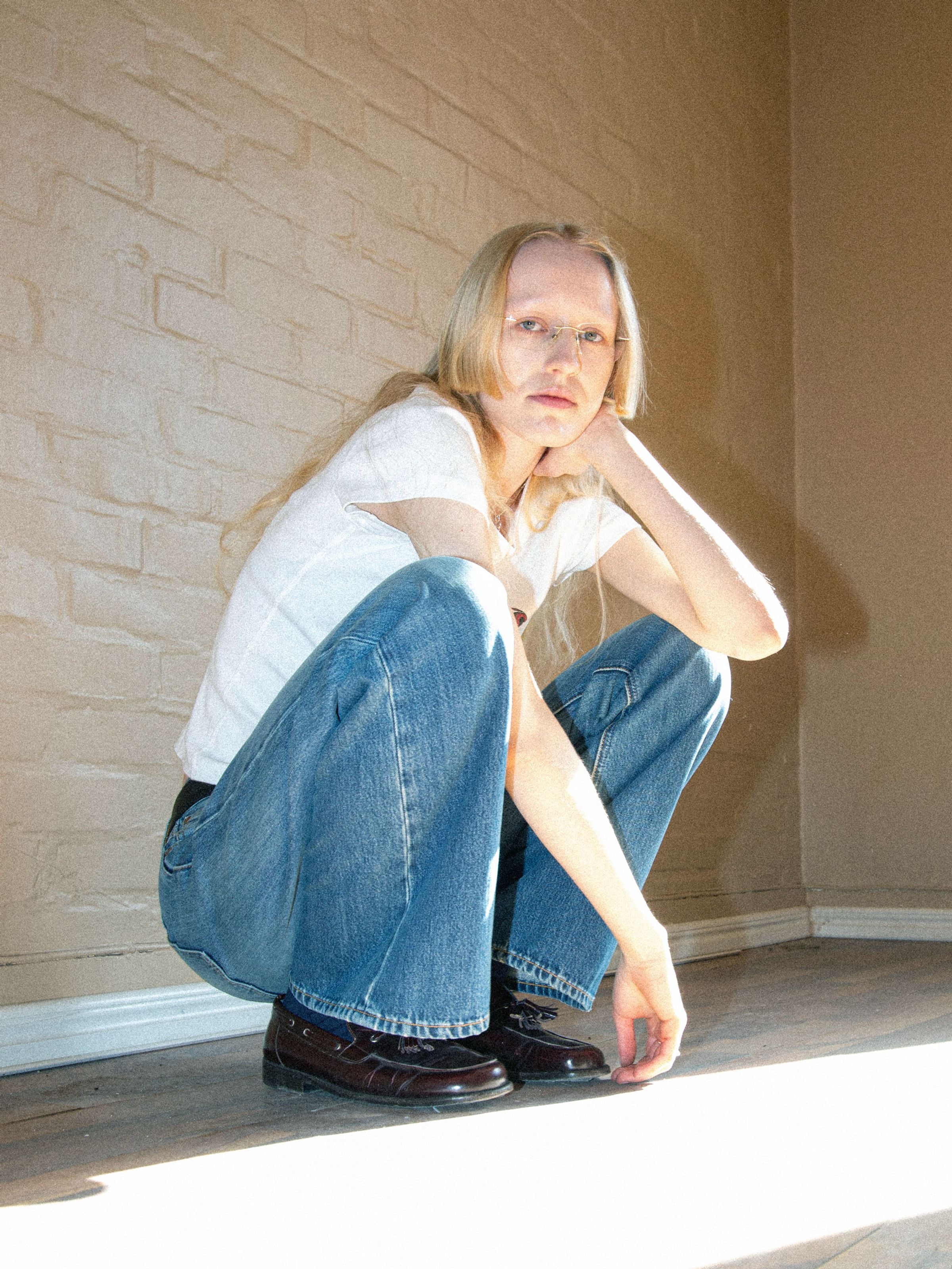Nudie Jeans Wide Heidi Gravel Stone, loose-fit wide-leg jeans in mid blue organic cotton, shown on a model squatting.