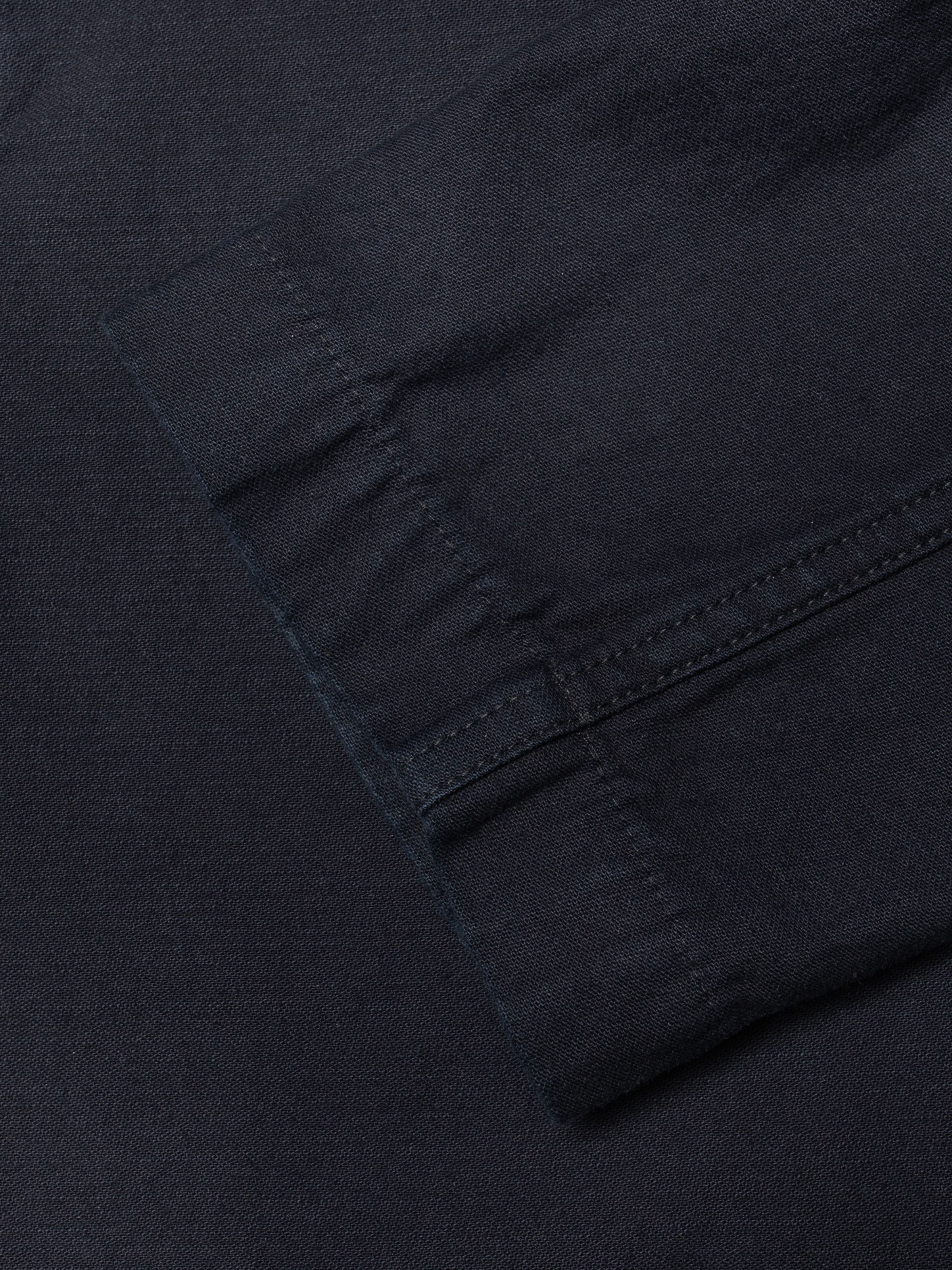 Nudie Jeans Lovis Jacket Back Sateen Indigo, Nahaufnahme des strukturierten Bio-Baumwollstoffs und der tonalen Nähte.