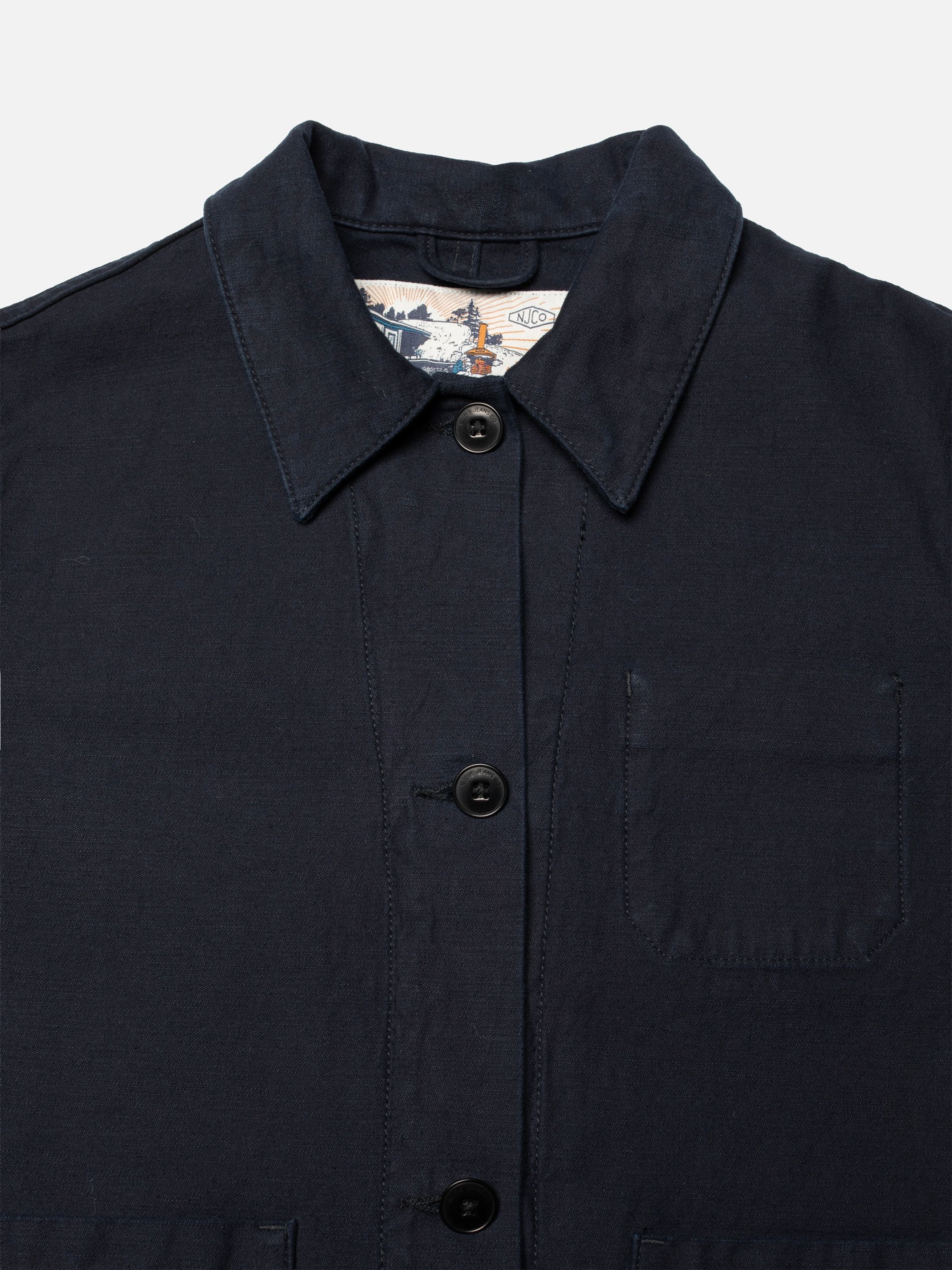 Nudie Jeans Lovis Jacket Back Sateen Indigo, Nahaufnahme des Kragens aus Bio-Baumwolle und schwarzer Corozo-Knöpfe.