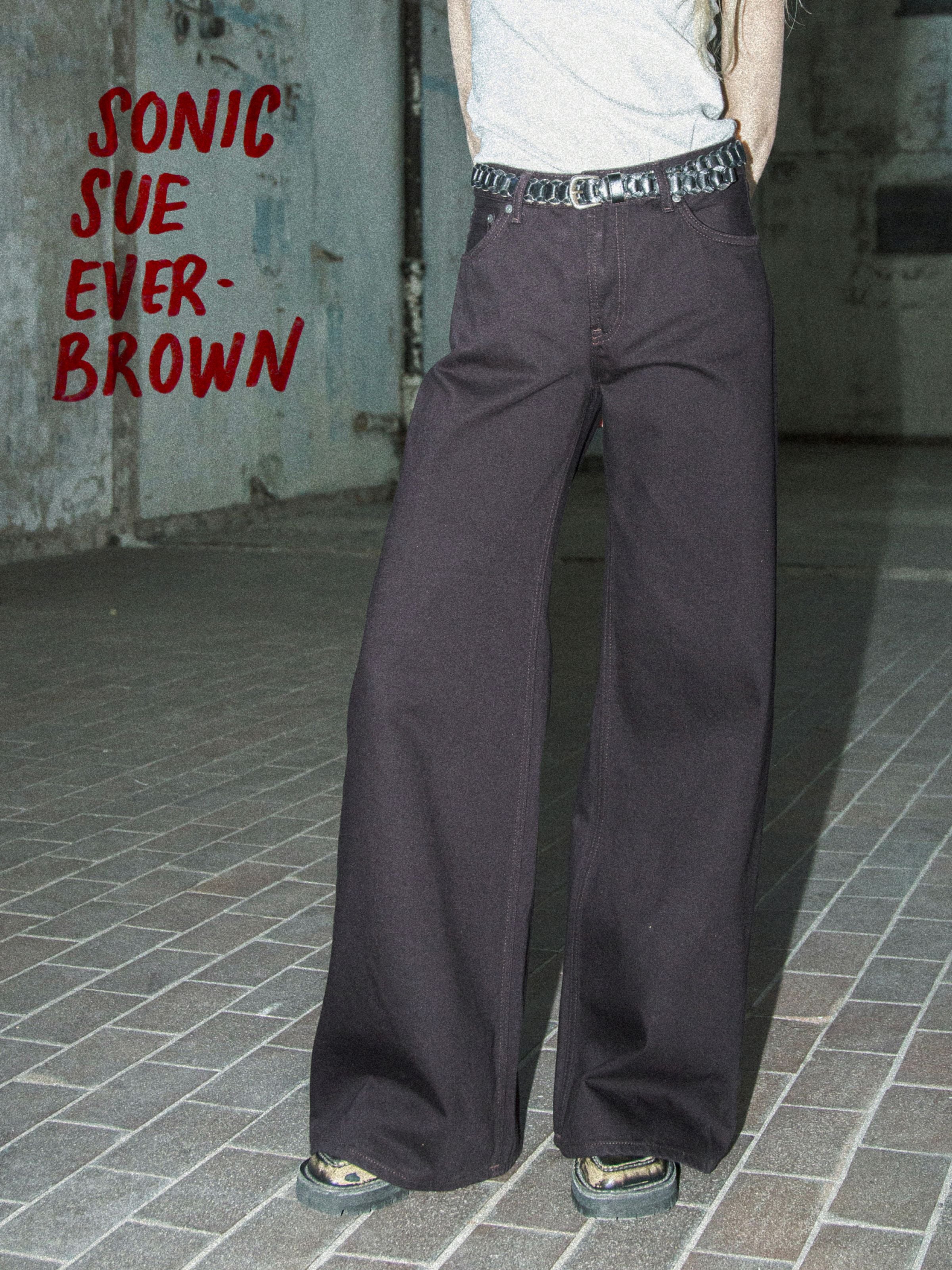 Nudie Jeans Sonic Sue Everbrown, lockere Jeans mit weitem Bein aus tiefbraunem Rigid Denim aus Bio-Baumwolle am Model.
