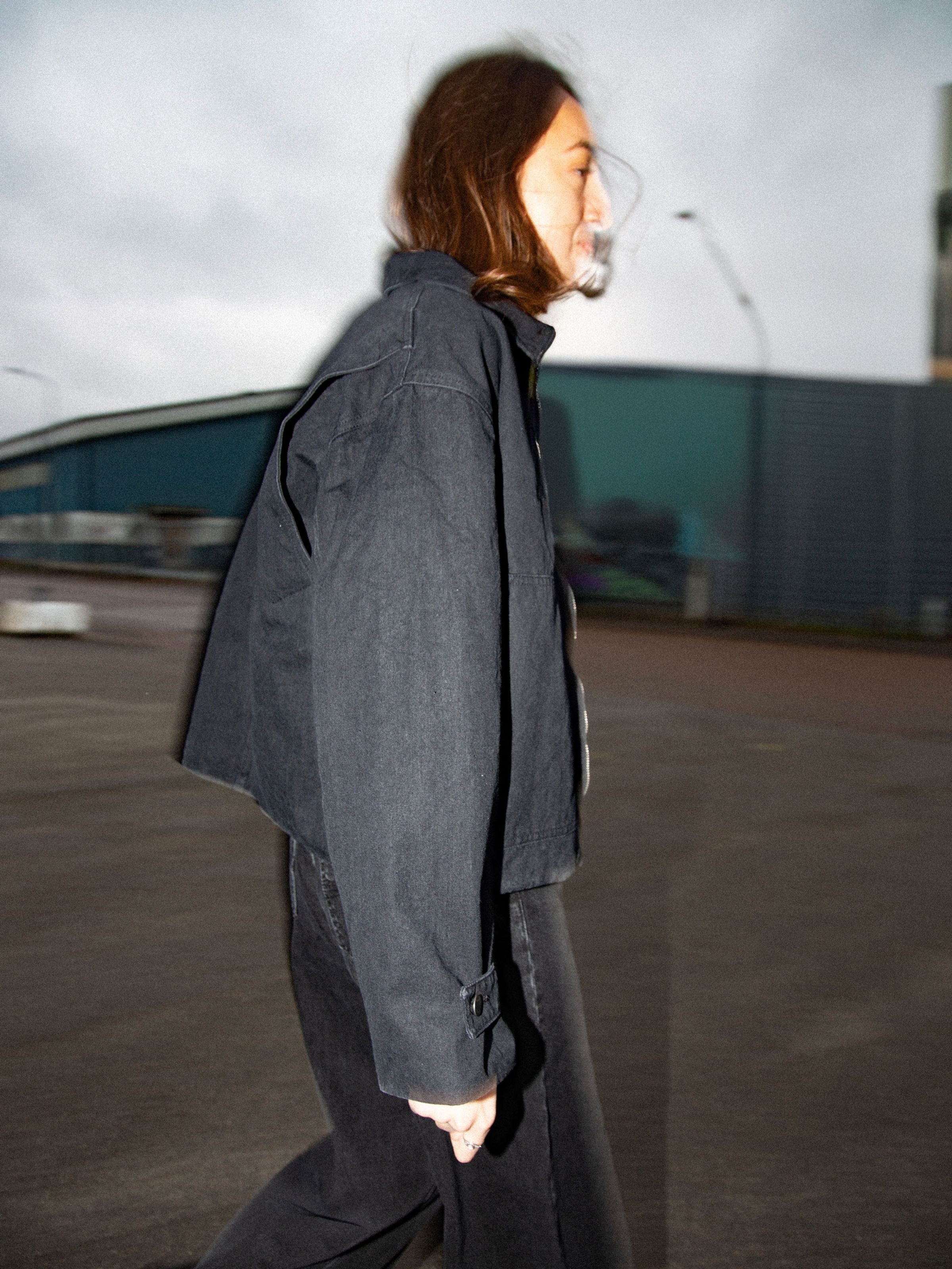 Nudie Jeans Lana Jacket in black organic cotton duck canvas, featuring a boxy fit, shown from the side on a model.