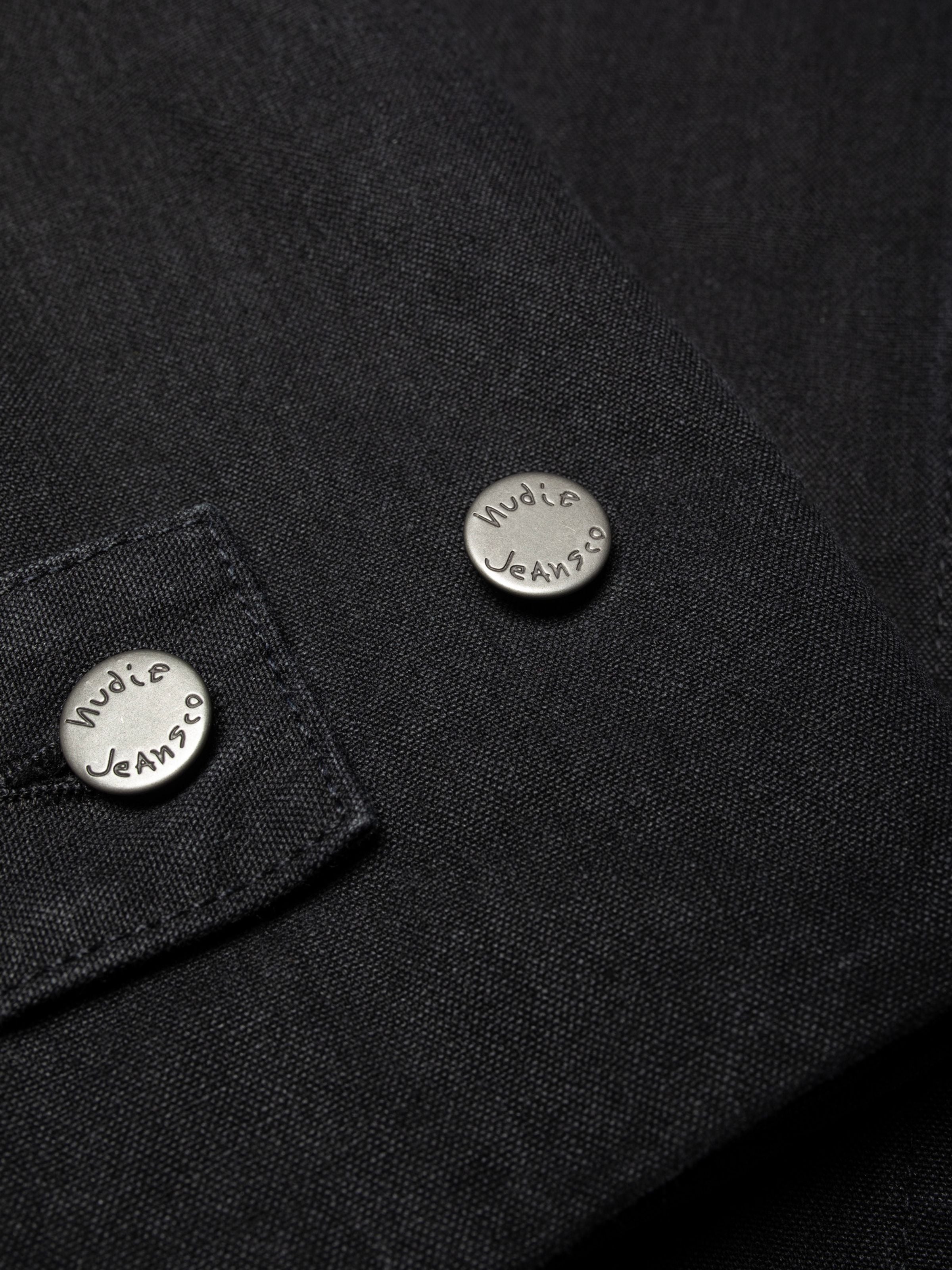 Nudie Jeans Lana Jacket Duck Canvas Black, close-up of branded metal buttons on the organic cotton fabric.