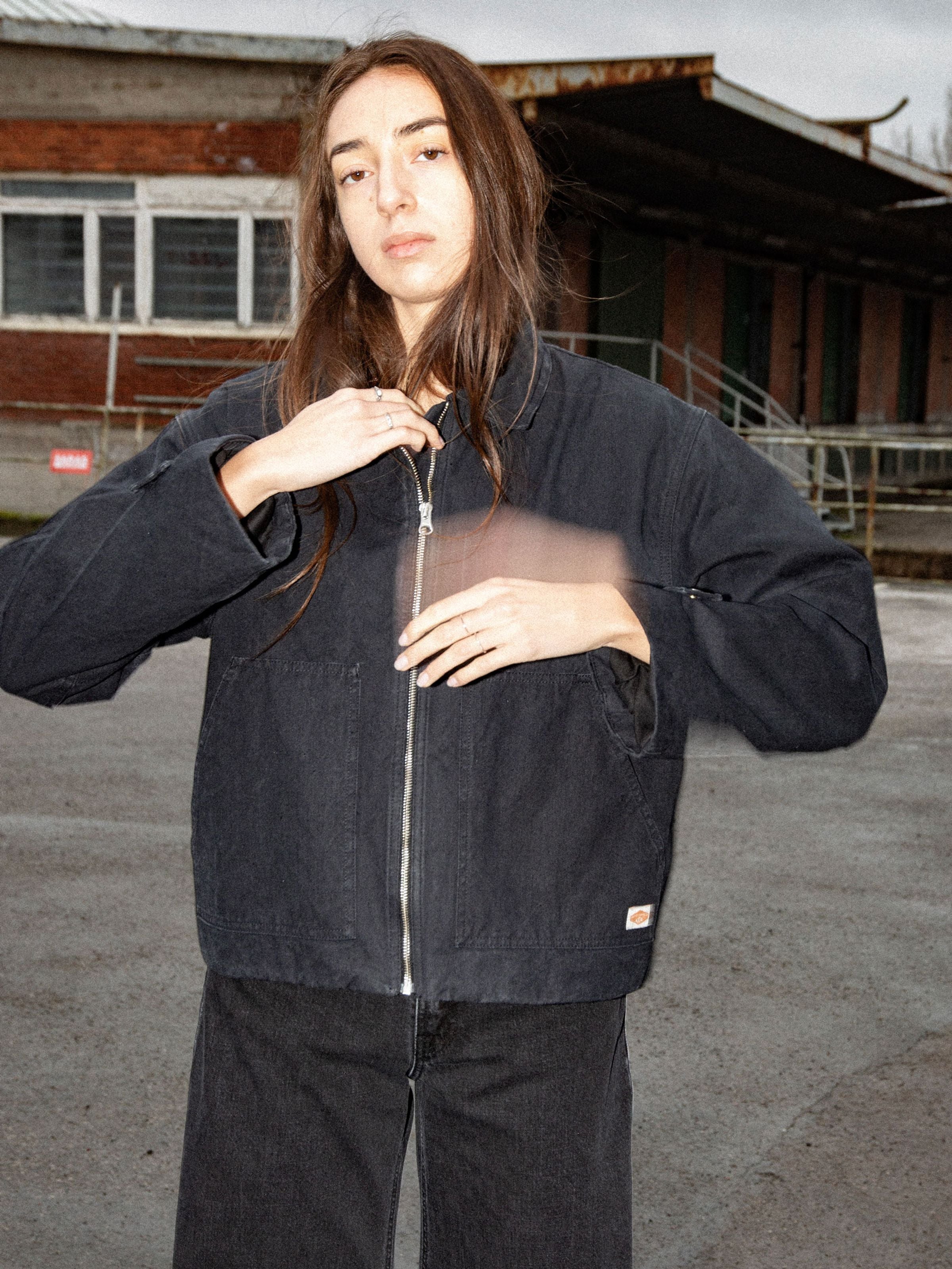 Nudie Jeans Lana Jacket Duck Canvas Black, a boxy zip-up jacket in organic cotton shown on a model in an outdoor setting.
