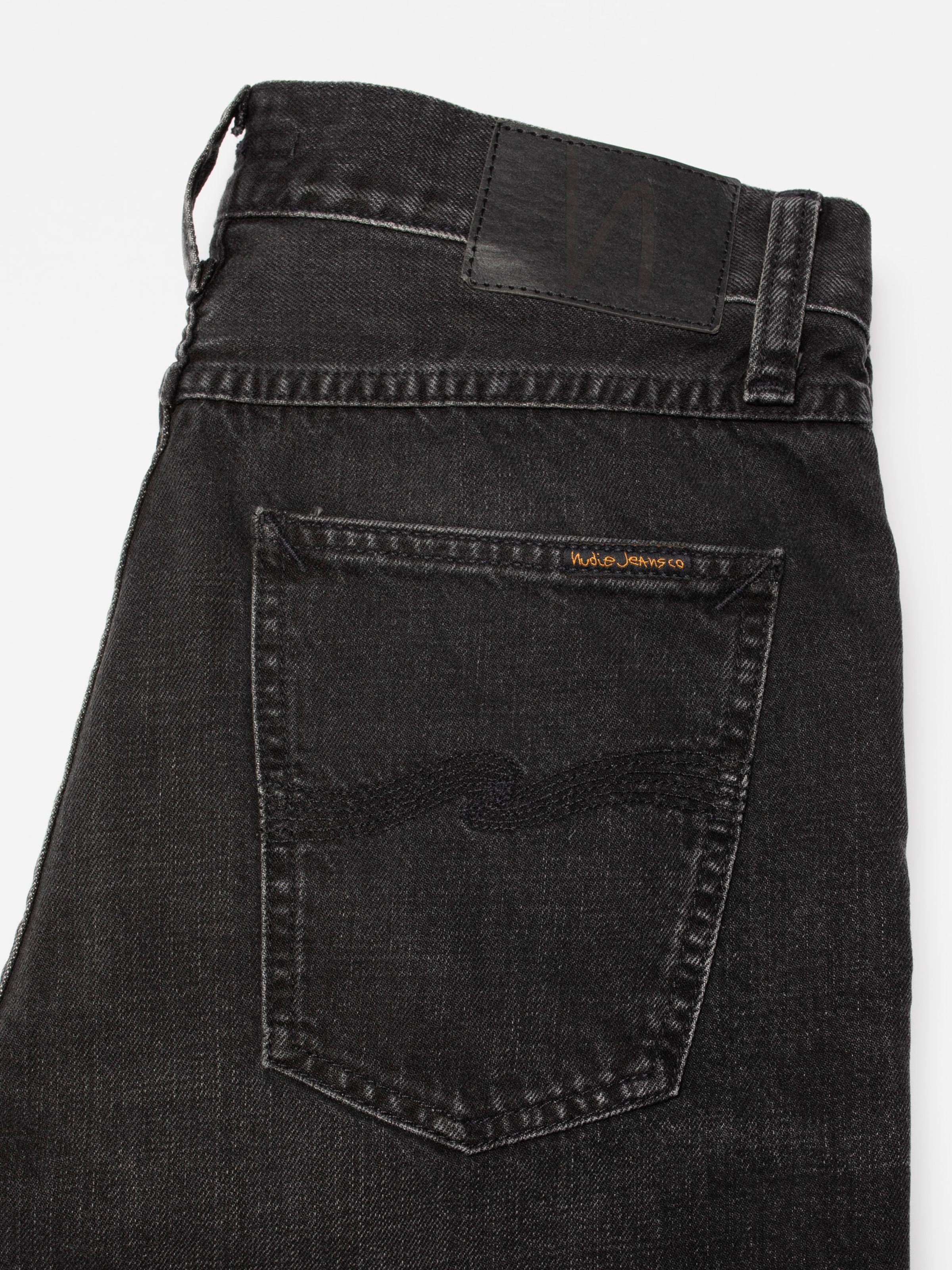 Nudie Jeans Steady Eddie II Black Fog, Nahaufnahme von Gesäßtasche und schwarzem Jacron-Patch auf Bio-Baumwoll-Denim.