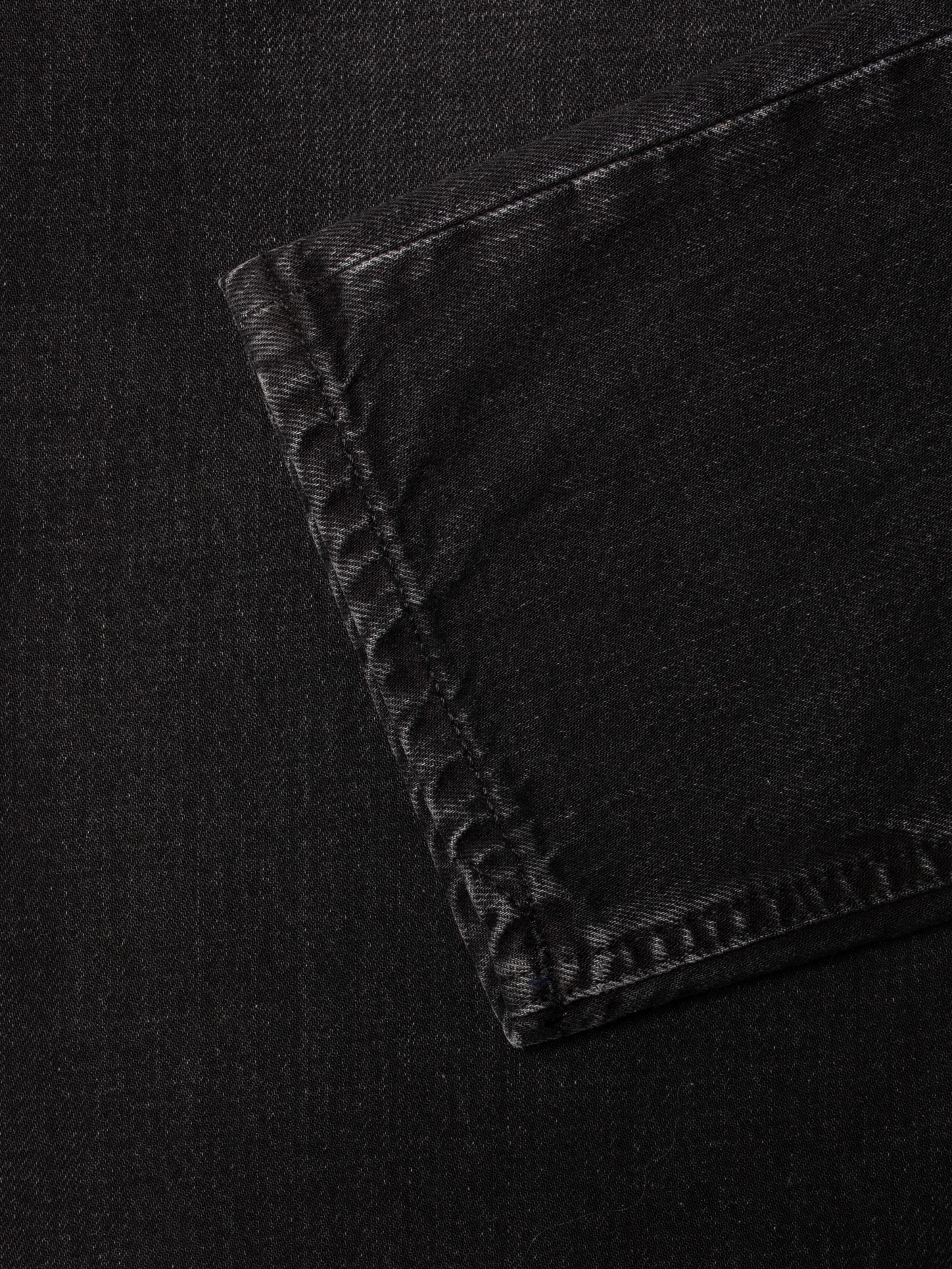 Nudie Jeans Steady Eddie II Black Fog, Nahaufnahme des Denims aus Bio-Baumwolle mit Naht und Salt-and-Pepper-Textur.